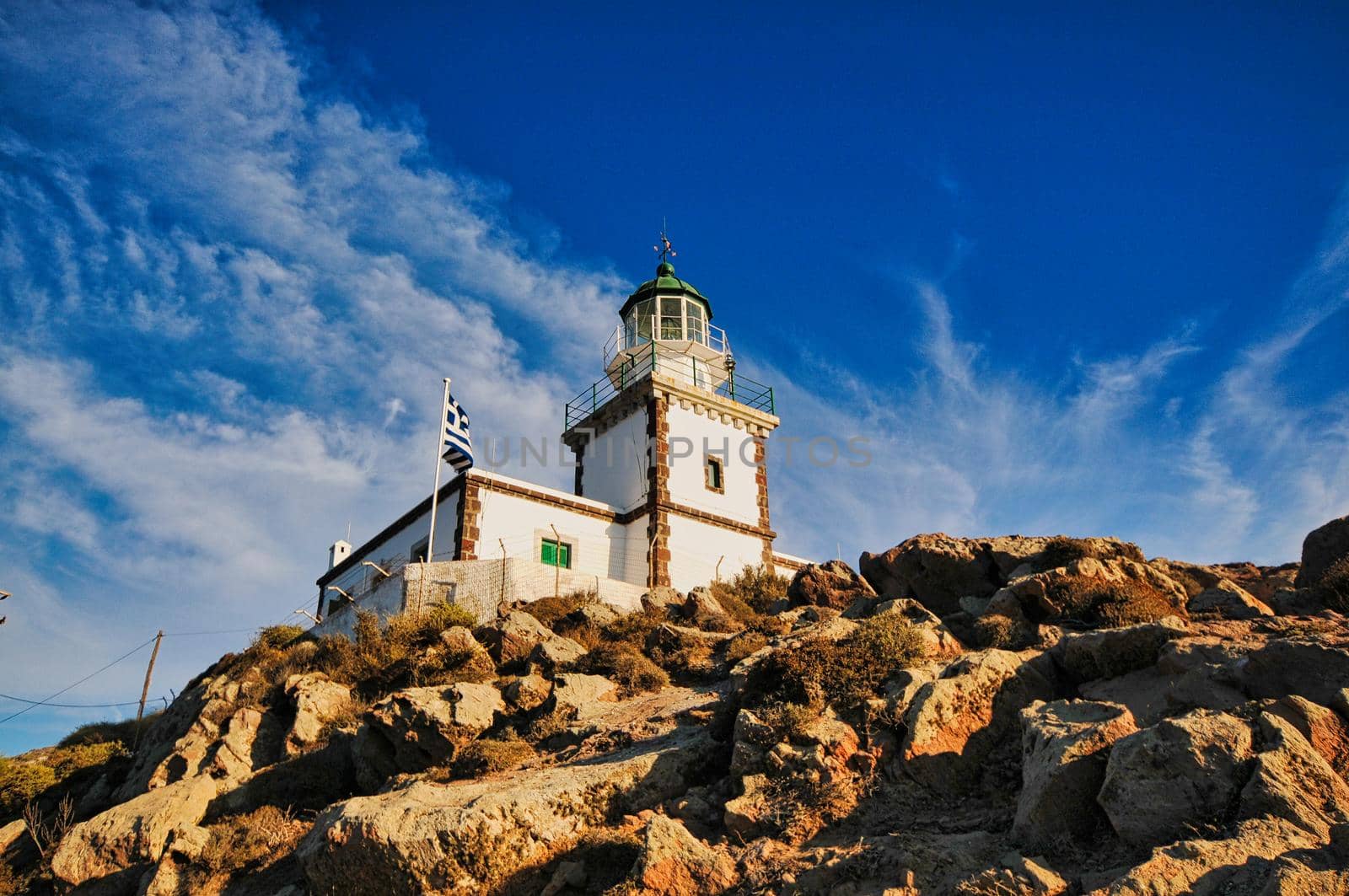 Lighthouse with greek flag in Santorini, cyclades island, with blue sky