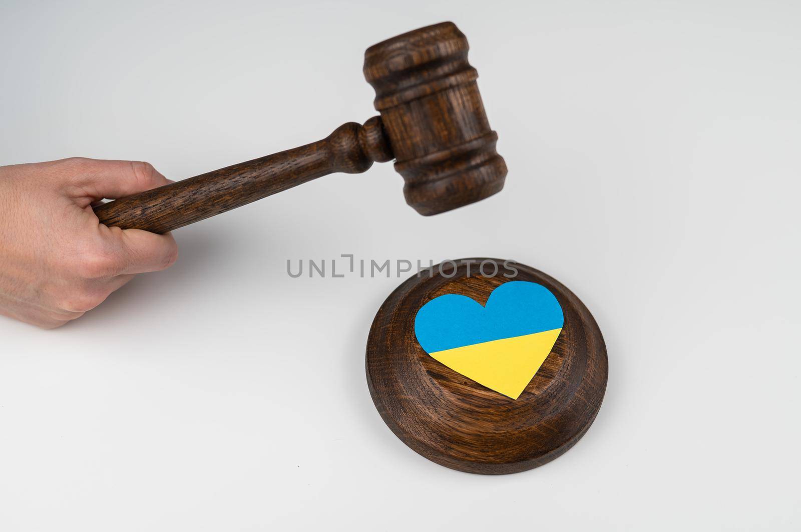 Woman hitting the judge's gavel on the heart with the flag of Ukraine on a white background