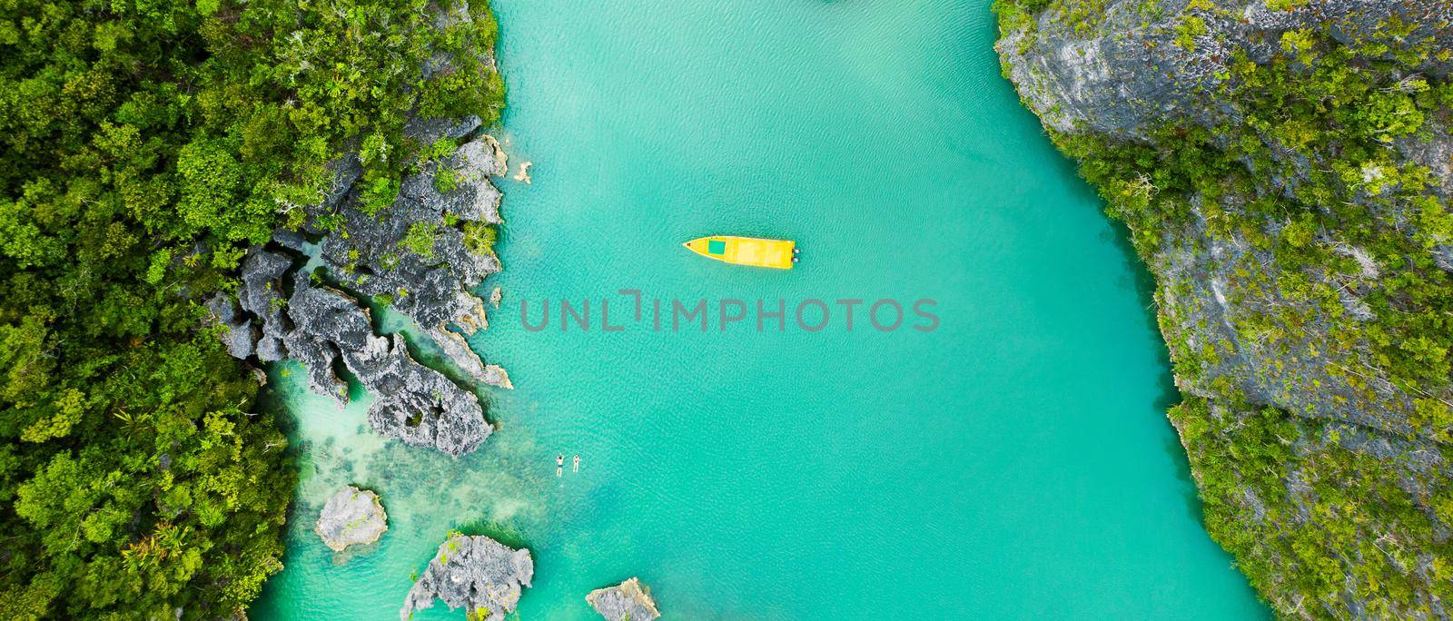 Kick off your summer with an island cruise. High angle shot of a boat sailing through a canal running along the Raja Ampat Islands in Indonesia. by YuriArcurs