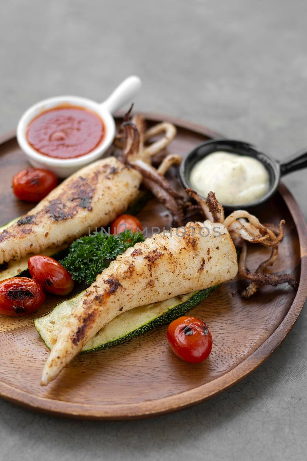 grilled whole squid with aioli and spicy sauce in spanish restaurant by jackmalipan