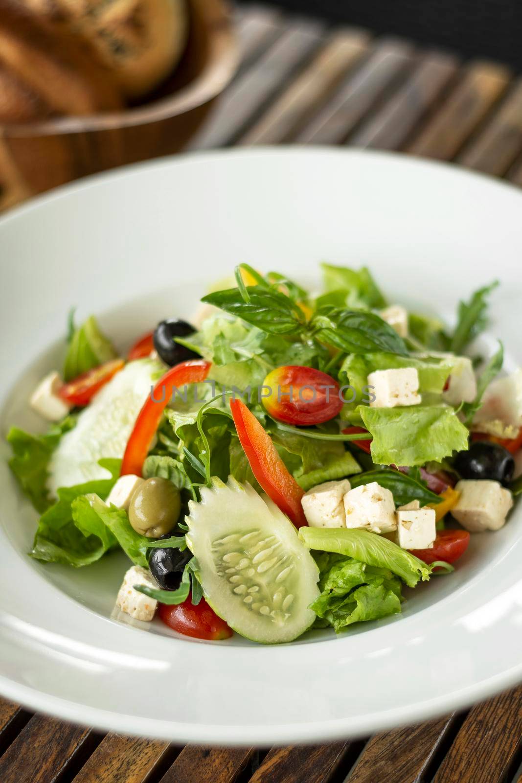 organic fresh greek salad with feta cheese on wood table by jackmalipan