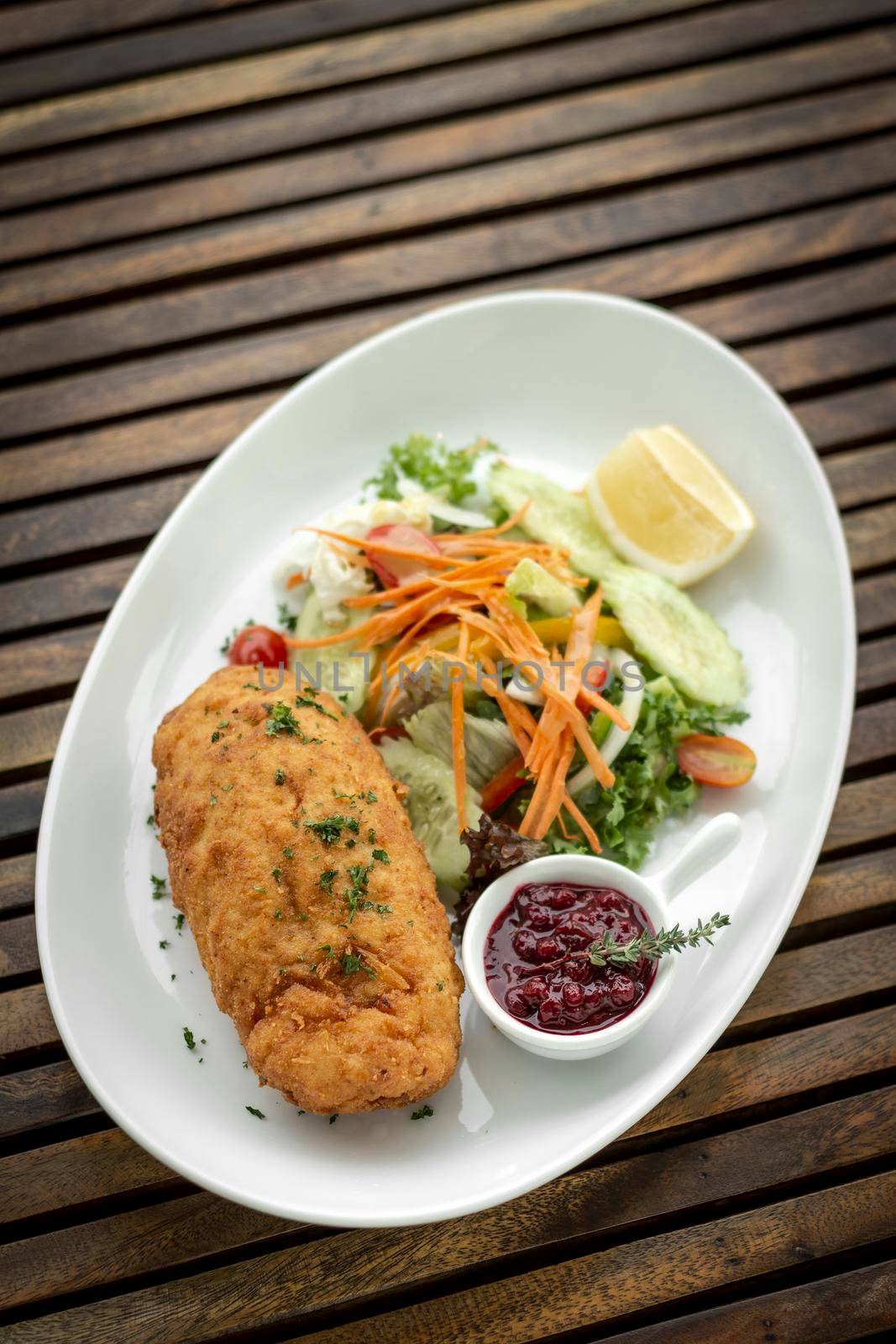 chicken cordon bleu meal with salad and red berry coulis in french restaurant