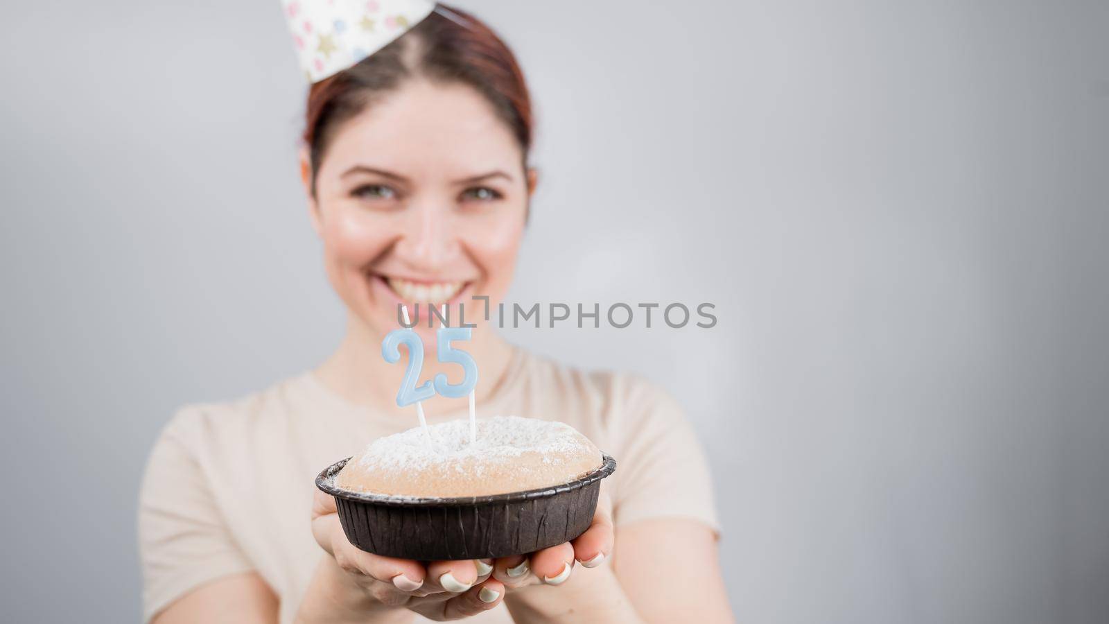 The happy woman makes a wish and blows out the candles on the 25th birthday cake. Girl celebrating birthday