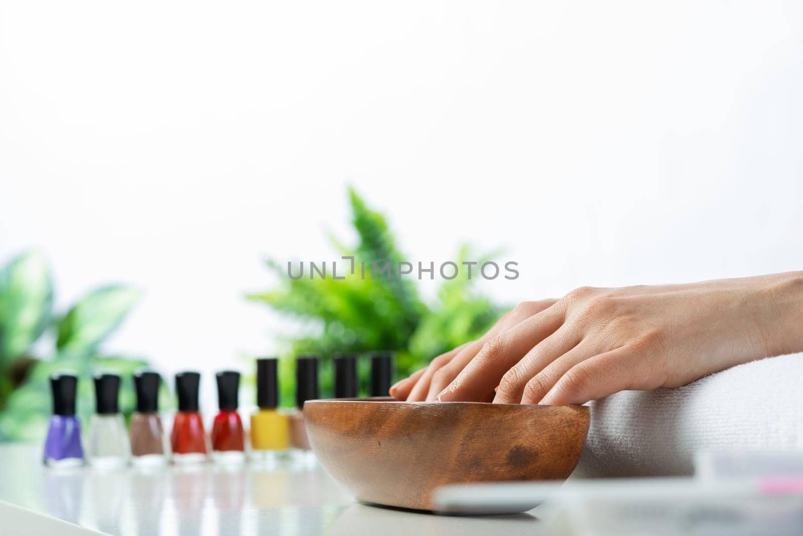 Woman hands in wooden bowl with water. Spa procedure and relaxation. Female hands preparing for manicure. Professional nail care and beautician service. Beauty and healthy lifestyle.