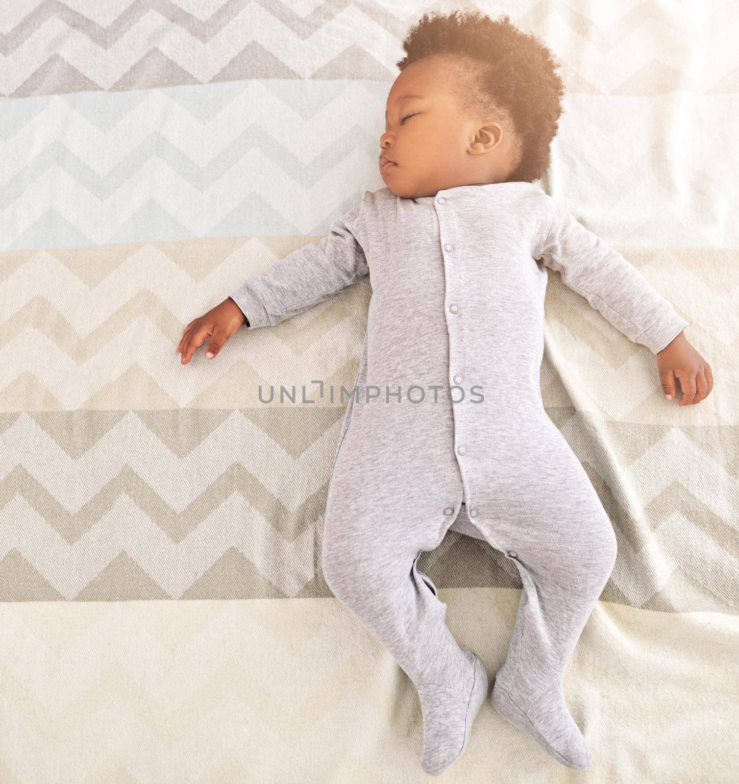 High angle shot of a little baby boy sleeping on a bed.