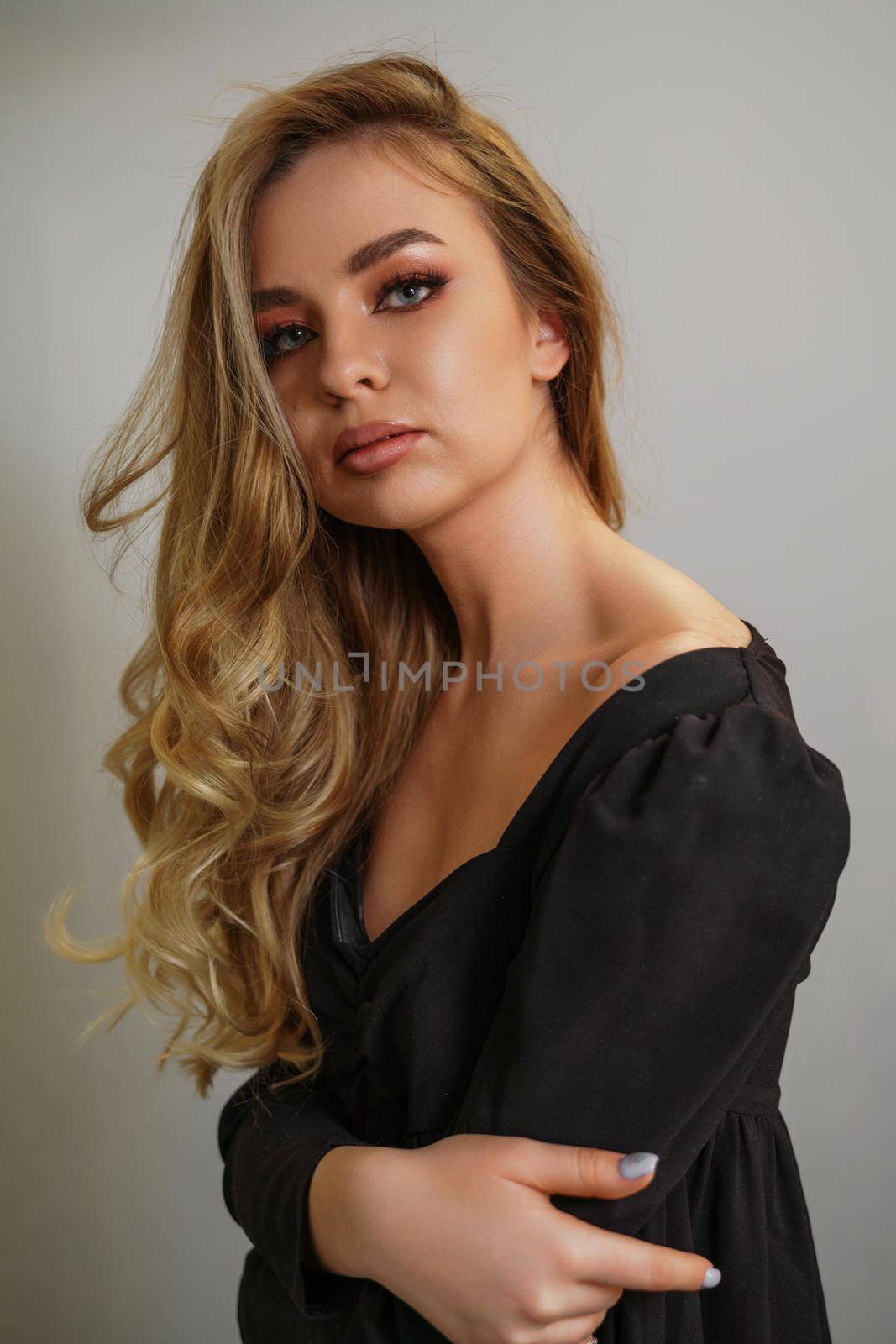 Beautiful young blonde woman face closeup portrait in studio on a light background by Matiunina