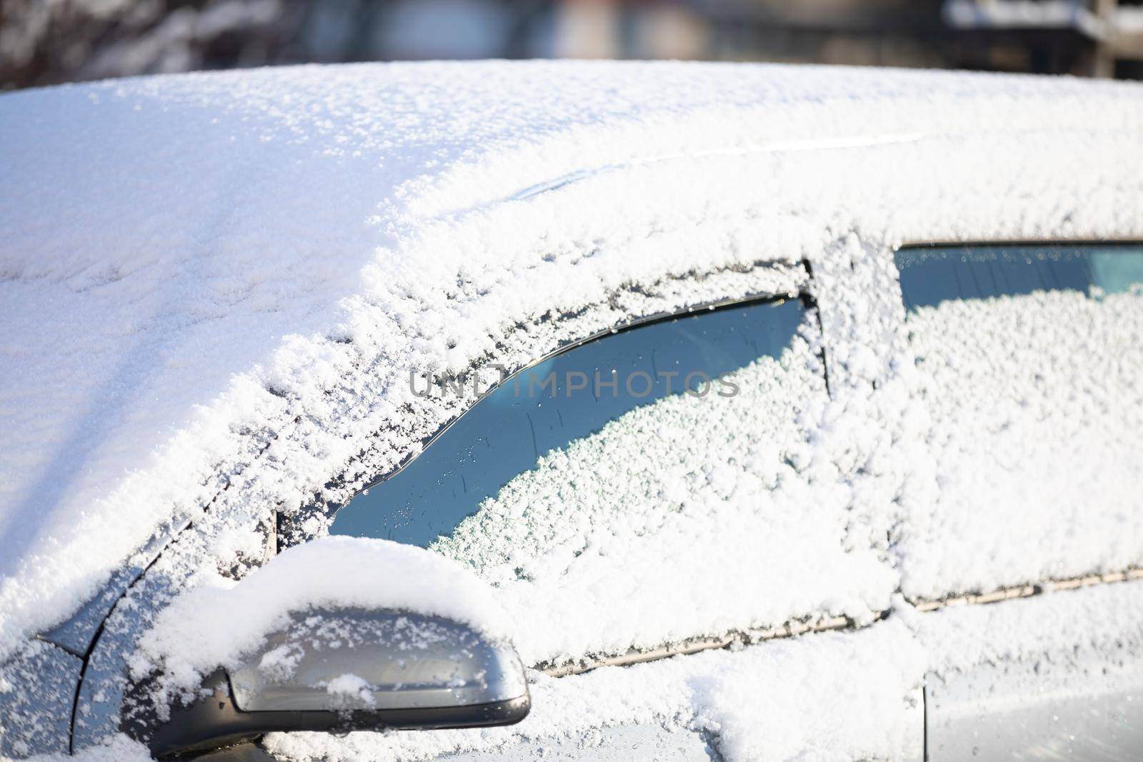 Snowfall covered the standing cars a city parking lot. The winter season brings snowfall and freezing temperatures.