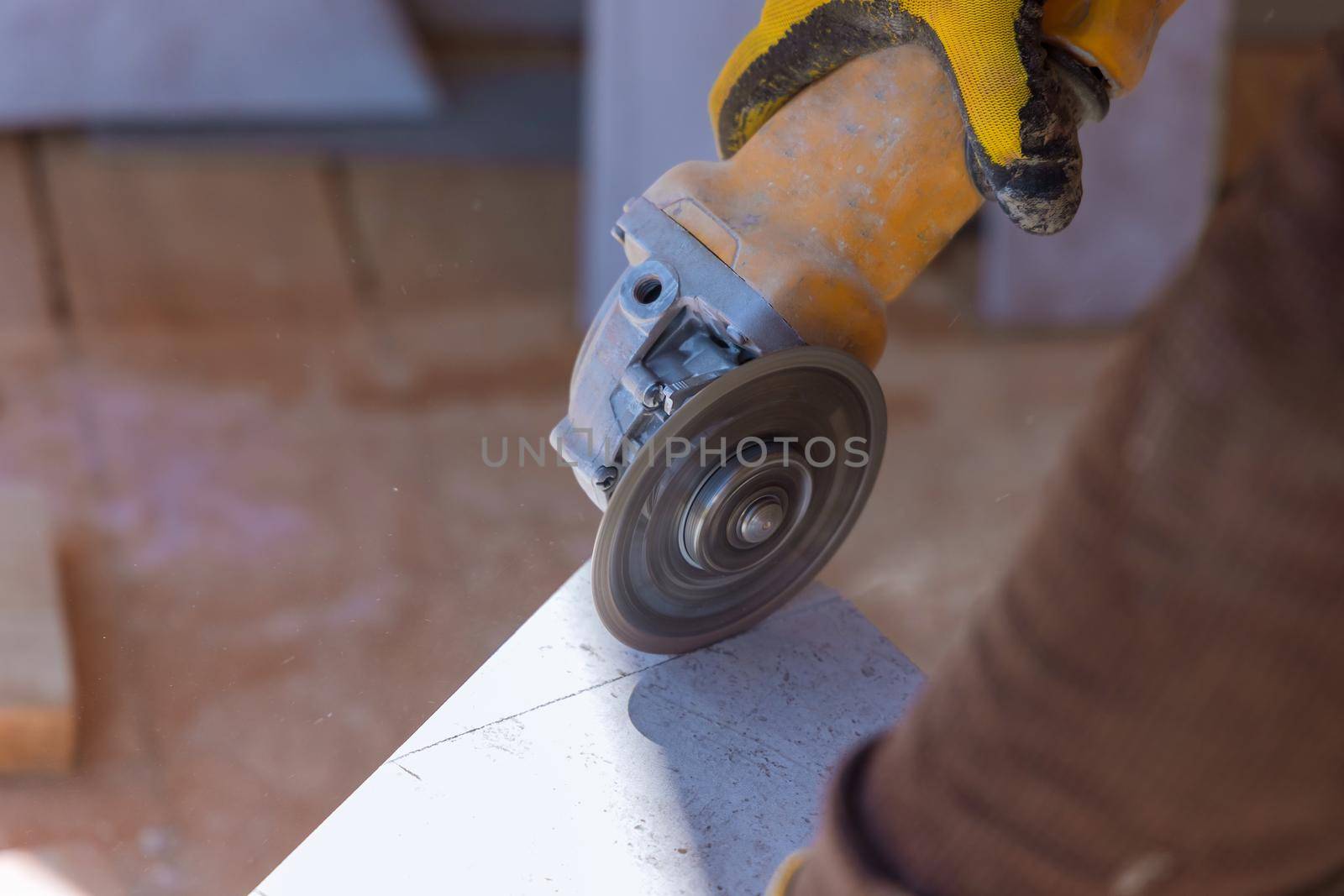 A man is cutting a floor ceramic tile with an circular saw
