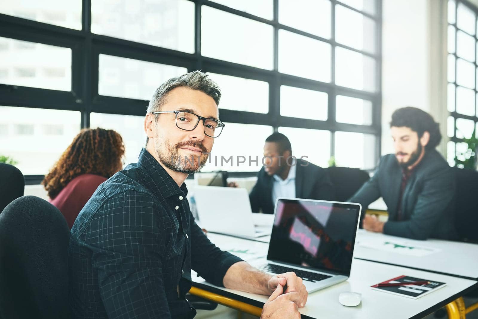 Ive got the best team in the business. Cropped portrait of a mature businessman working at a desk with his colleagues in the office. by YuriArcurs