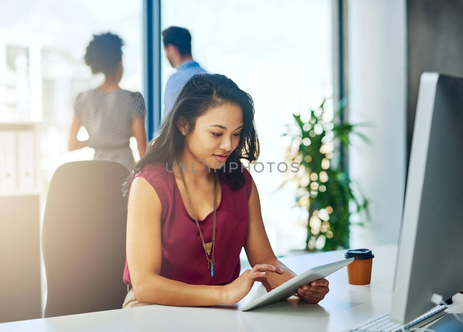 Working towards her deadlines with the aid of technology. Cropped shot of a young businesswoman working on a digital tablet in a modern office. by YuriArcurs