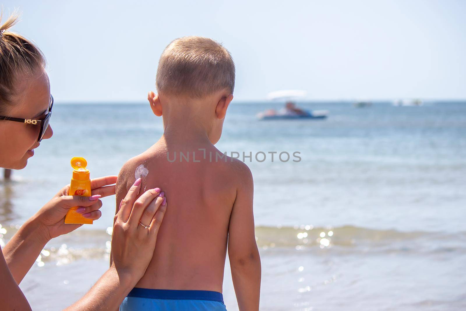 Mother puts cream on her son's back. Caring for baby skin. Sunscreens in the travel. selective focus