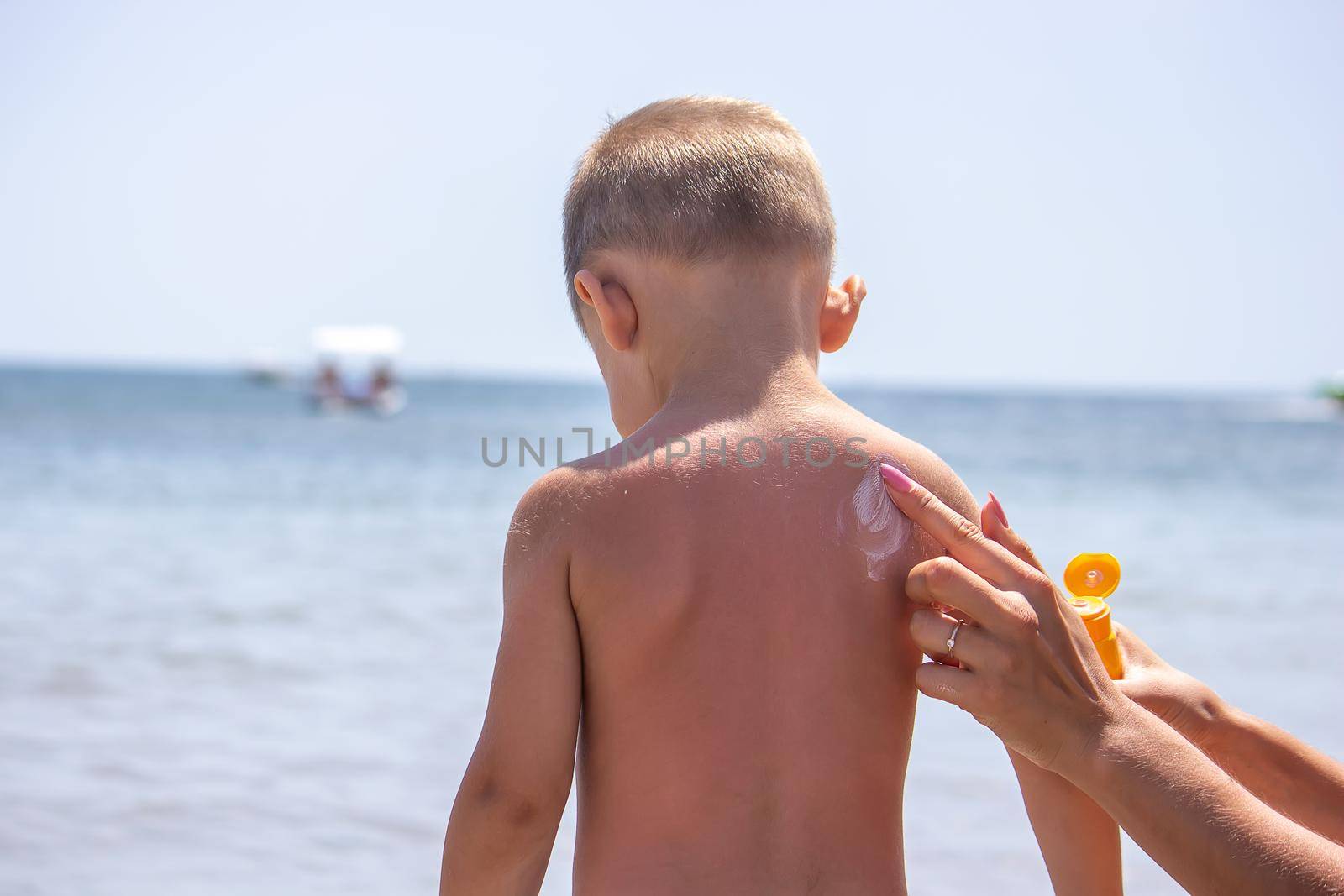 Mother puts cream on her son's back. Caring for baby skin. Sunscreens in the travel. selective focus
