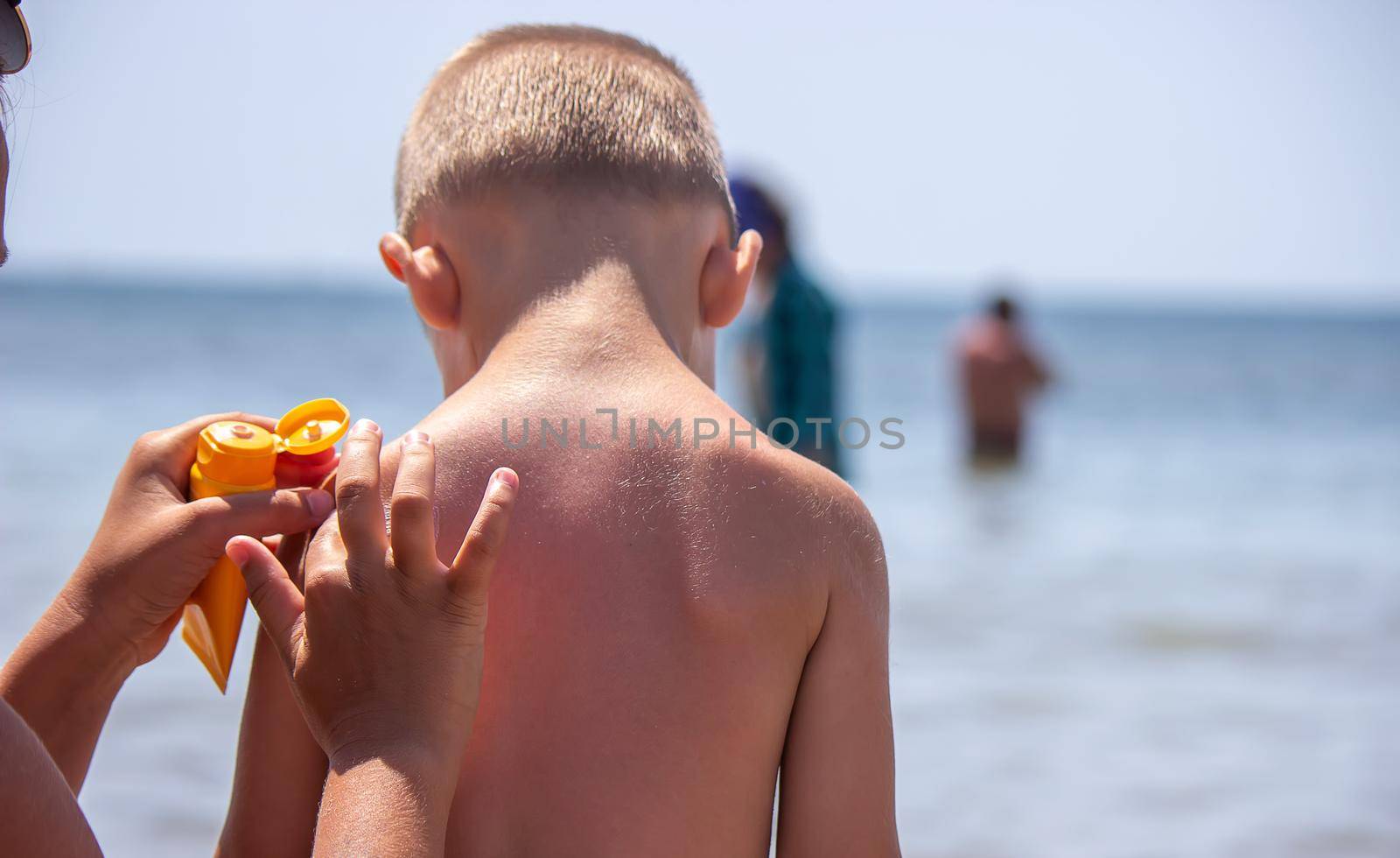 Mother puts cream on her son's back. Caring for baby skin. Sunscreens in the travel. selective focus