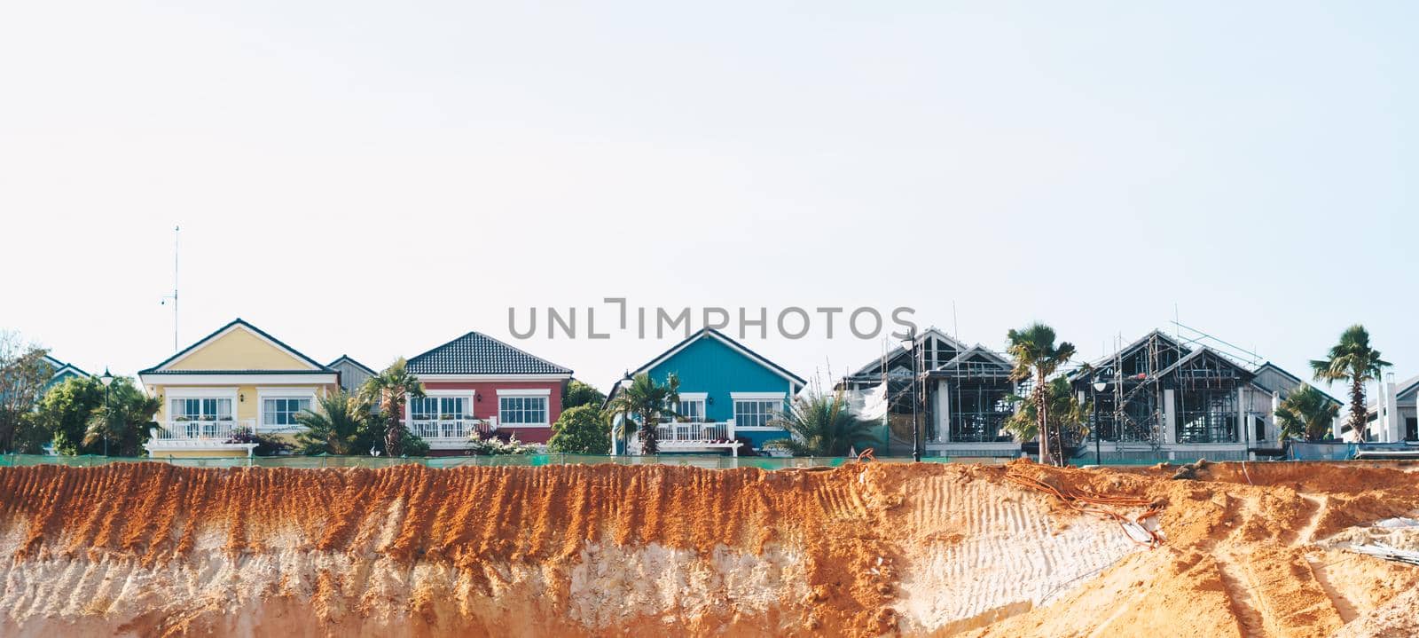BANNER. Scenic view colorful yellow red blue small village facade roofs houses, new buildings construction modern town place. Orange clay high hill. Azure summer sun sky. Panorama real nature frame.