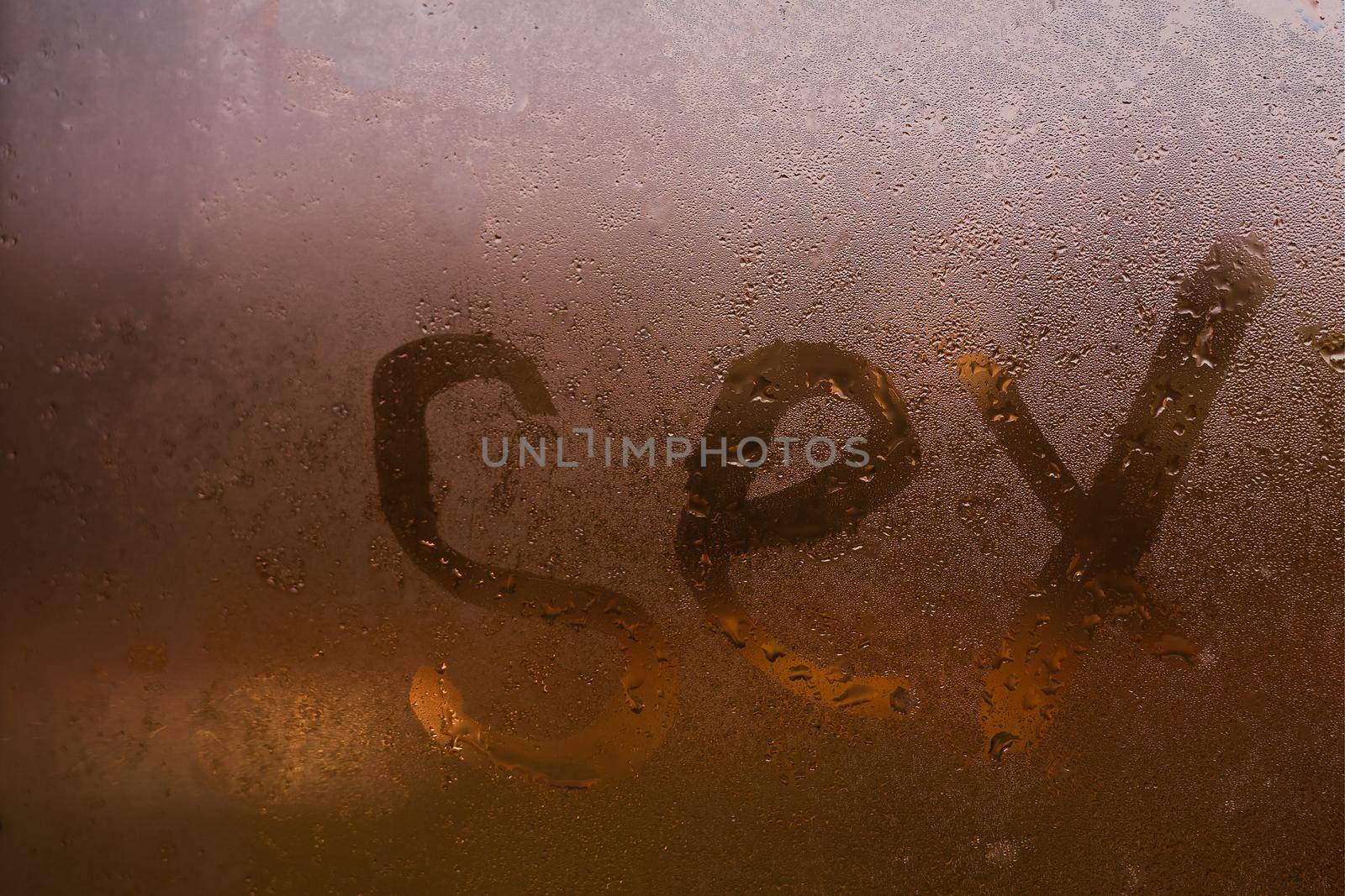 Closeup sign of sex on the foggy window glass with dripping drops condensated background, sensual steamy abstraction.