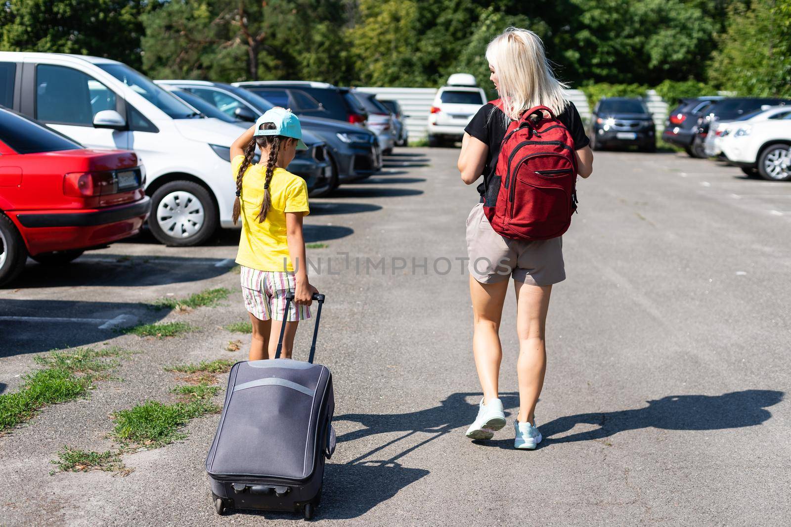 mother and daughter with suitcase in the parking lot by Andelov13