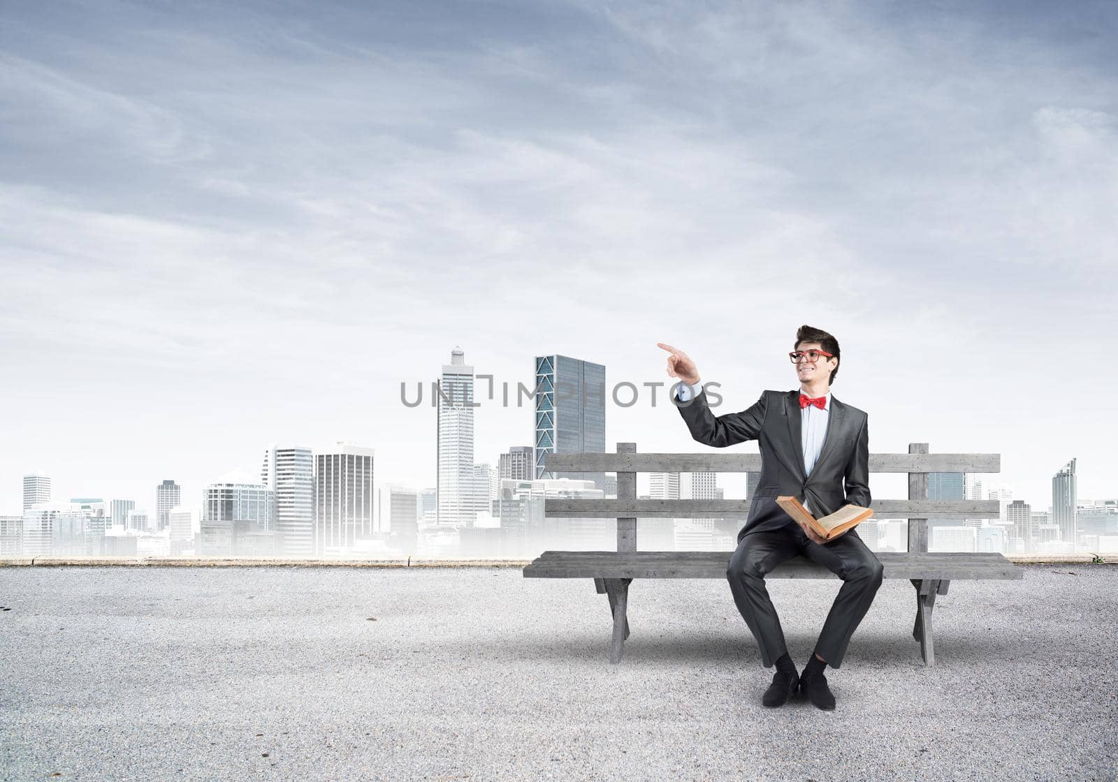 Student sits on a bench, holding a book. Traditional education concept