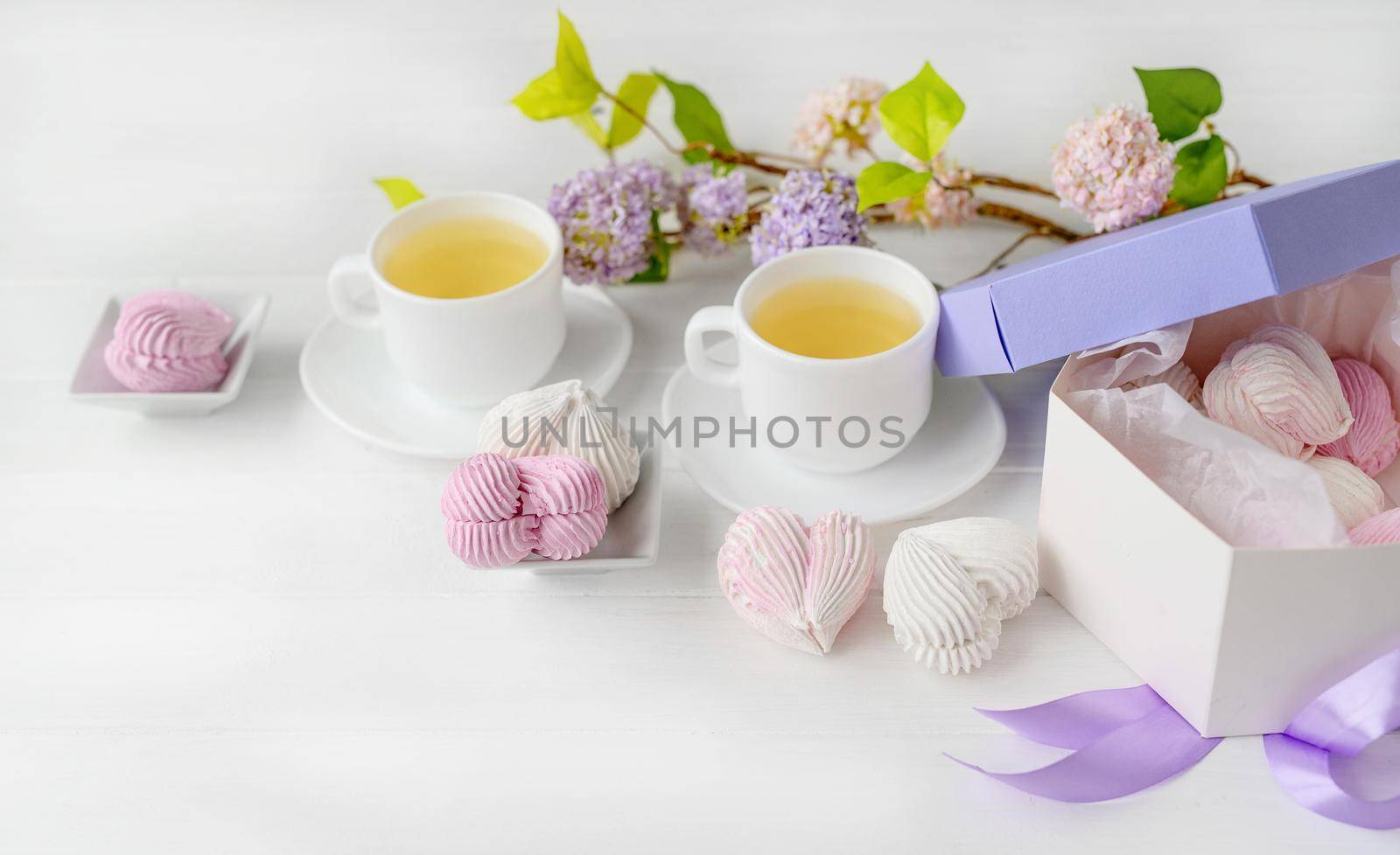 Heart shape marshmallows and cups with tea romantic composition. Craft desert sweets with beverage
