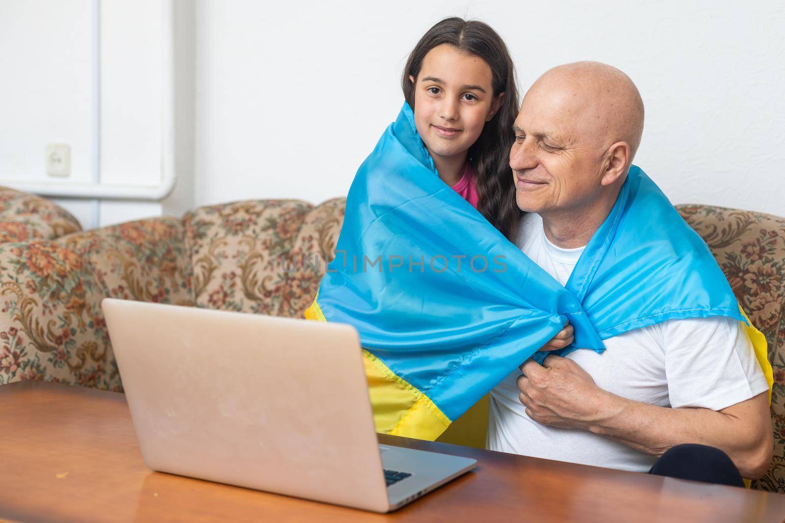 Grandfather and granddaughter with laptop and flag of Ukraine by Andelov13