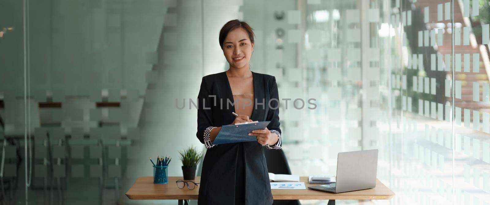 Portrait confidence business asian woman standing while working for financial accounting with laptop and calculator by nateemee