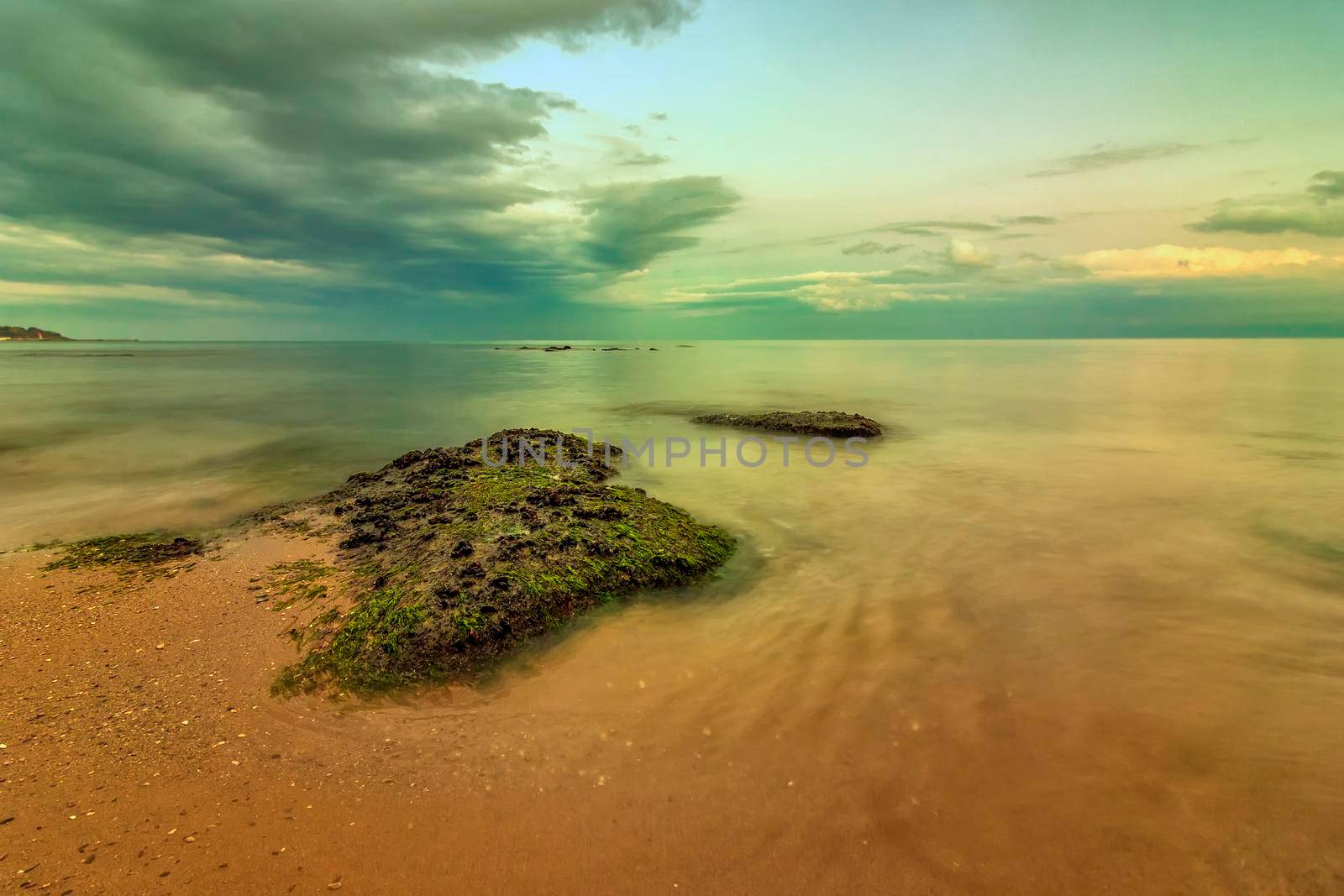 Seascape view of a calm sea with rocks with moss. Beauty sky with clouds at the horizon.  by EdVal