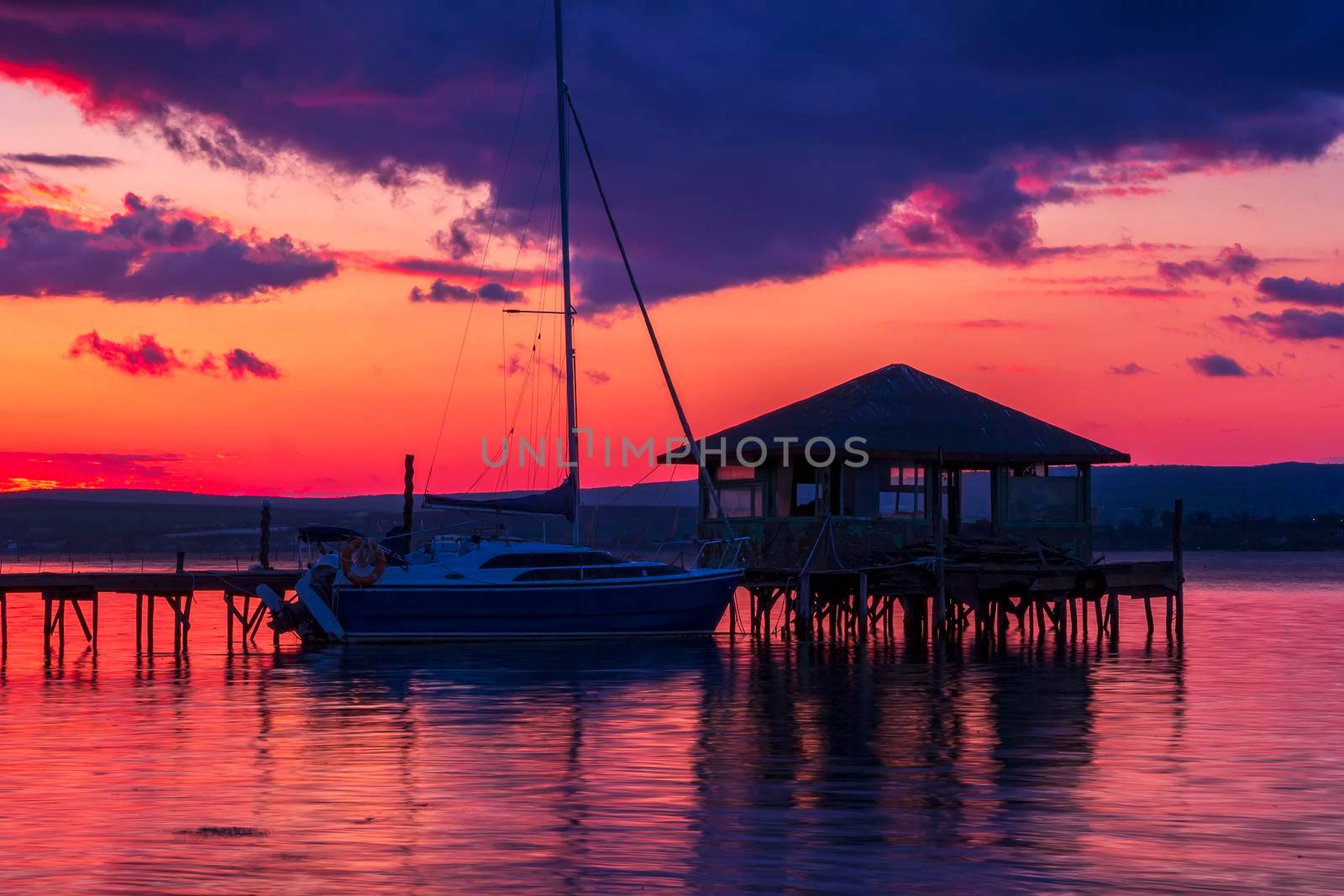 Exciting long exposure landscape on a lake with Yacht and wooden small house in the water