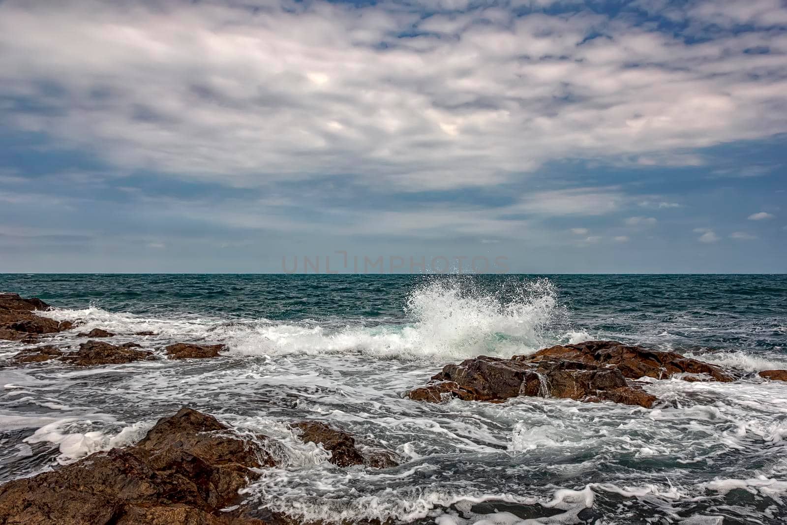 The stunning seascape with the cloudy sky and sea waves at the rocky coastline of the Black Sea