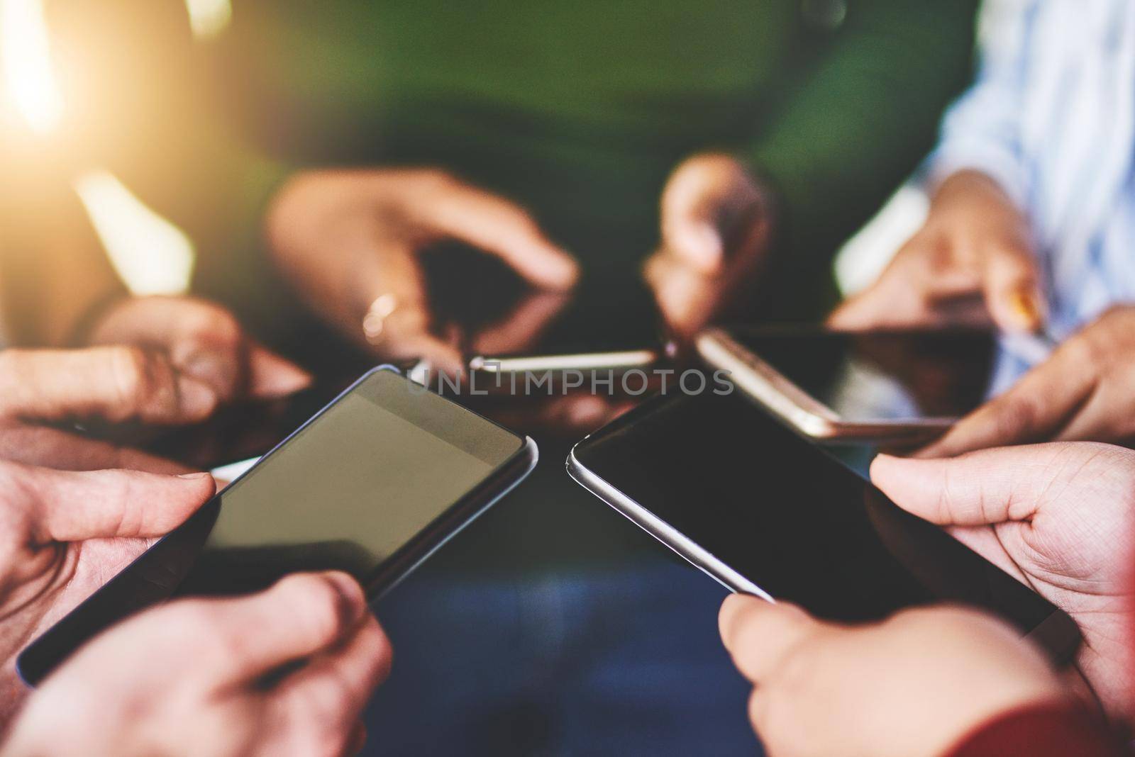Cropped shot of a group of people using their phones together.