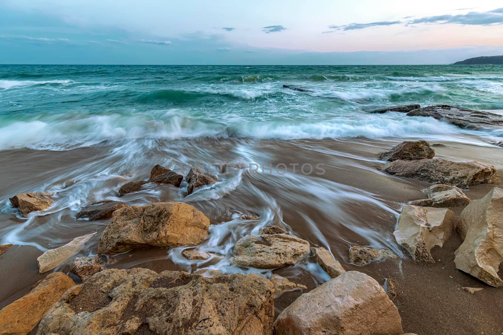 Stunning long exposure seascape with waves flowing between rocks.
