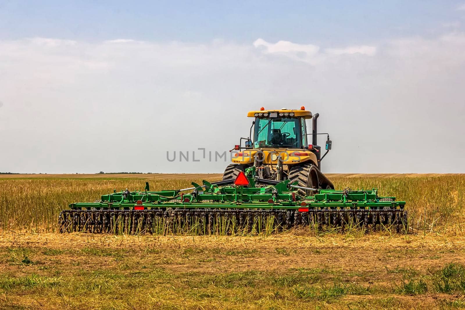 The tractor ready to prepare the ground for sowing and cultivation. Agriculture and agronomy concept. by EdVal