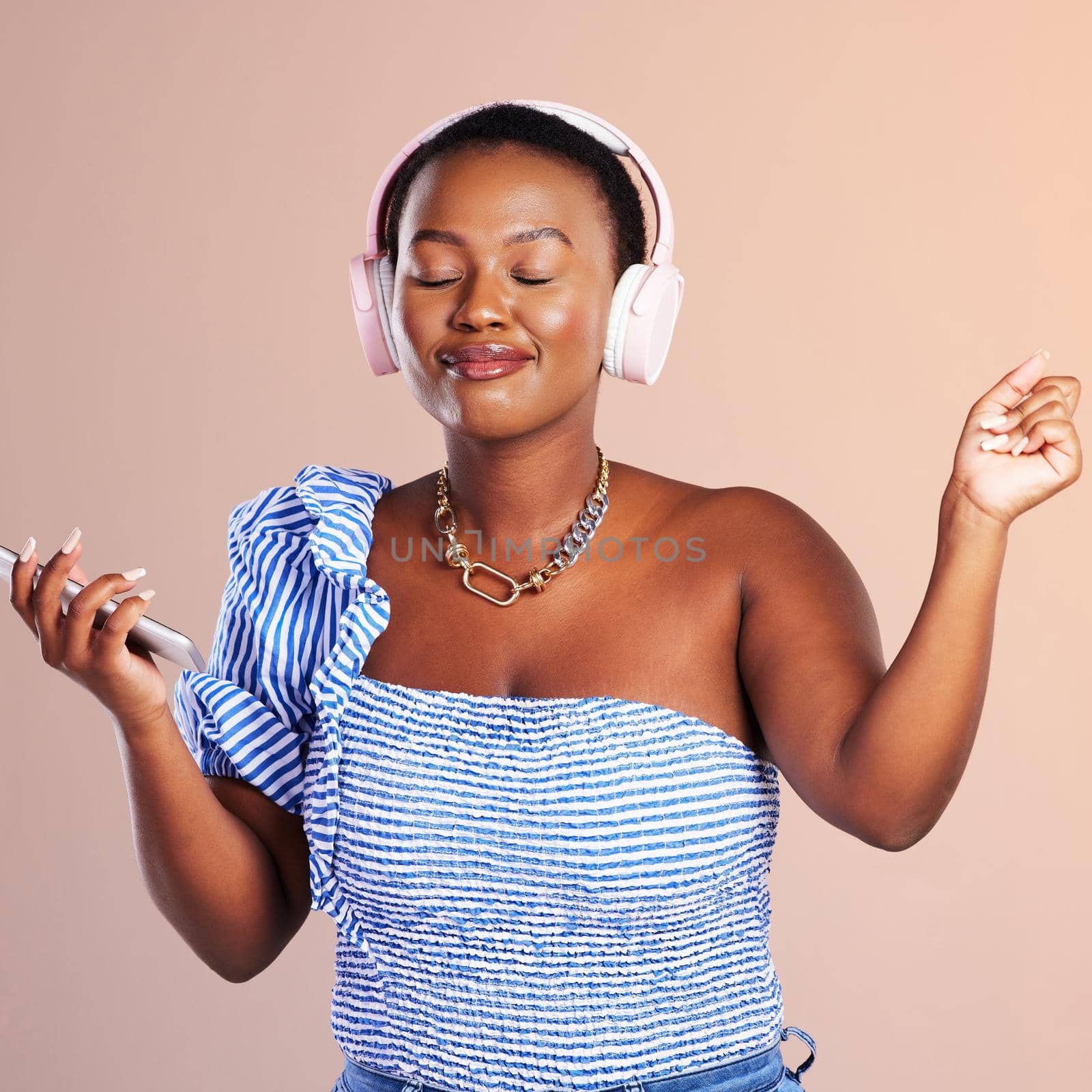 Music, a universal language. The universal healer. Studio shot of a young woman using a smartphone and headphones against a pink background. by YuriArcurs