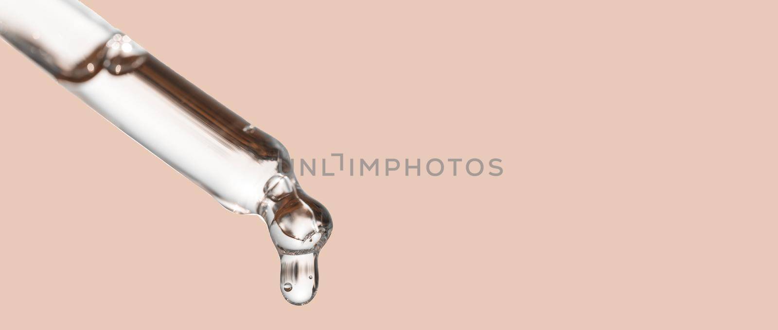 Cosmetics dropper, falling drop close up. Closeup of cosmetic pipette with essential oil dropping, serum with peptides on beige background. Beauty skin care product. Banner