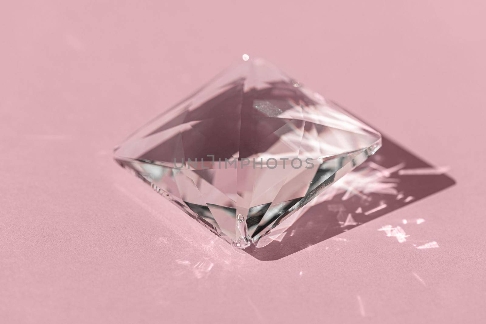 Crystal prism with light diffraction of spectrum colours and reflection with trendy light and hard shadows on pink background. Light spectrum reflected through glass prism. Banner