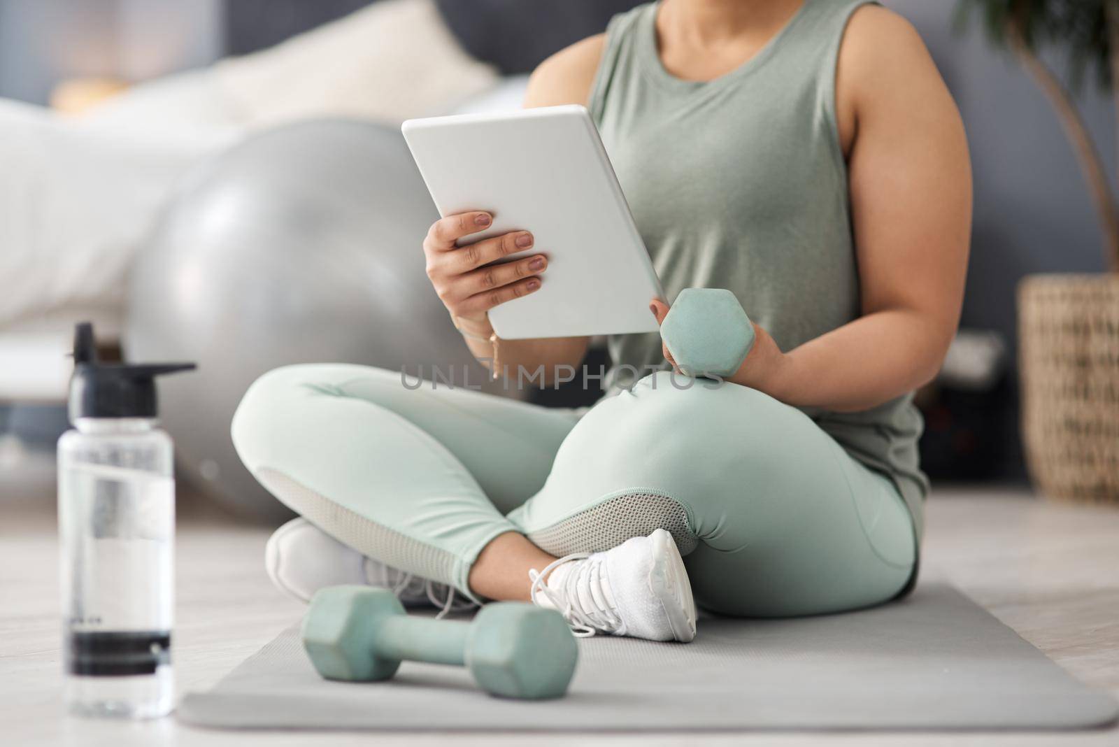Closeup shot of an unrecognisable woman using a digital tablet while exercising at home.