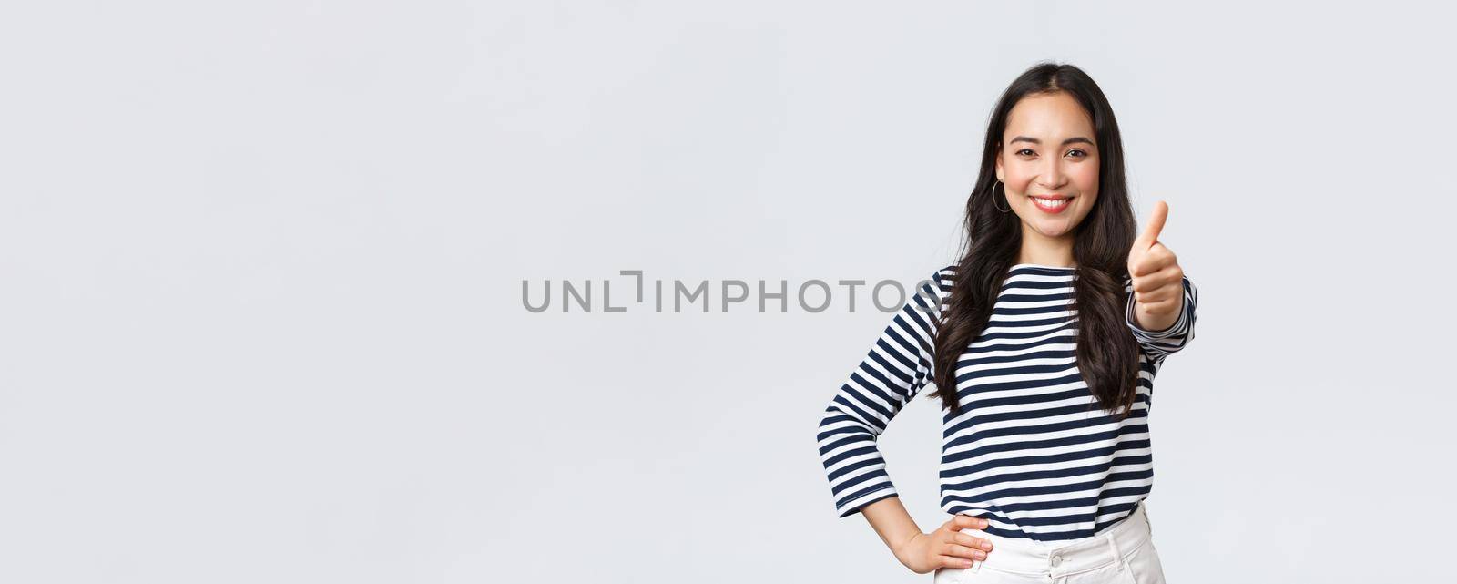 Lifestyle, beauty and fashion, people emotions concept. Cheerful cute asian girl thumb-up in approval, wink encouraging and smiling, praising nice job, say well played as congratulate with win.