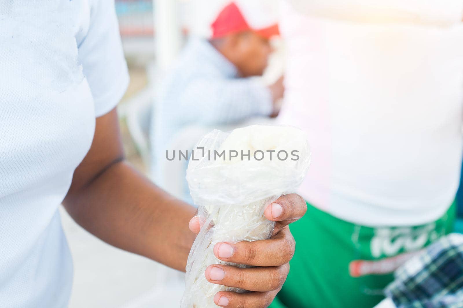 Closeup of the hands of a Nicaraguan woman holding a traditional dish called quesillo tucked in a plastic bag, a thin sheet of artisanal mozarella cheese on a corn tortilla