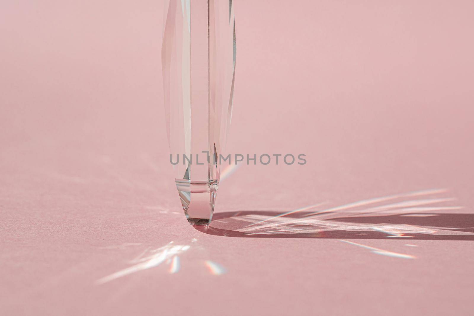 Crystal prism with light diffraction of spectrum colours and reflection with trendy light and hard shadows on pink background. Light spectrum reflected through glass prism. by photolime