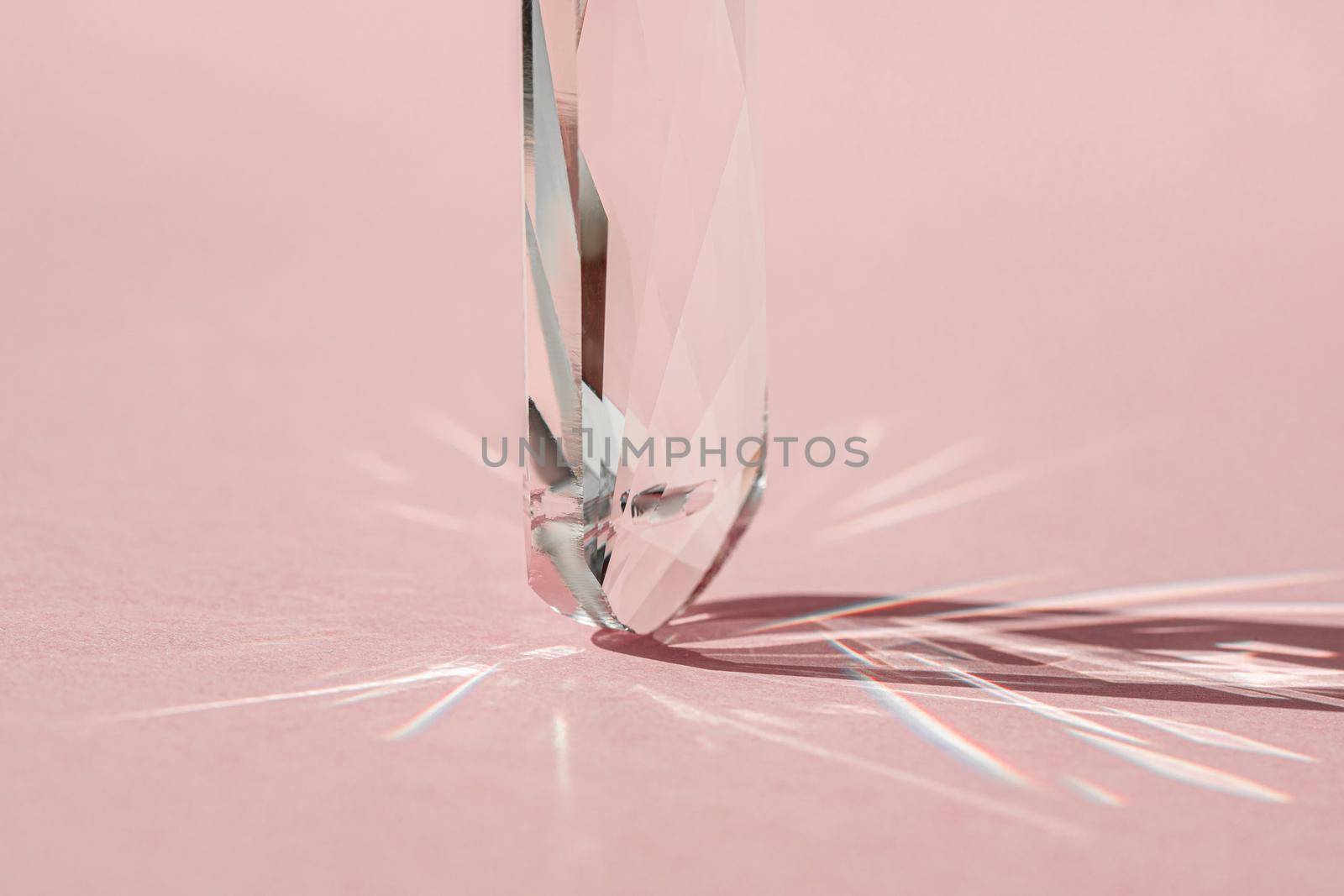 Crystal prism with light diffraction of spectrum colours and reflection with trendy light and hard shadows on pink background. Light spectrum reflected through glass prism. by photolime