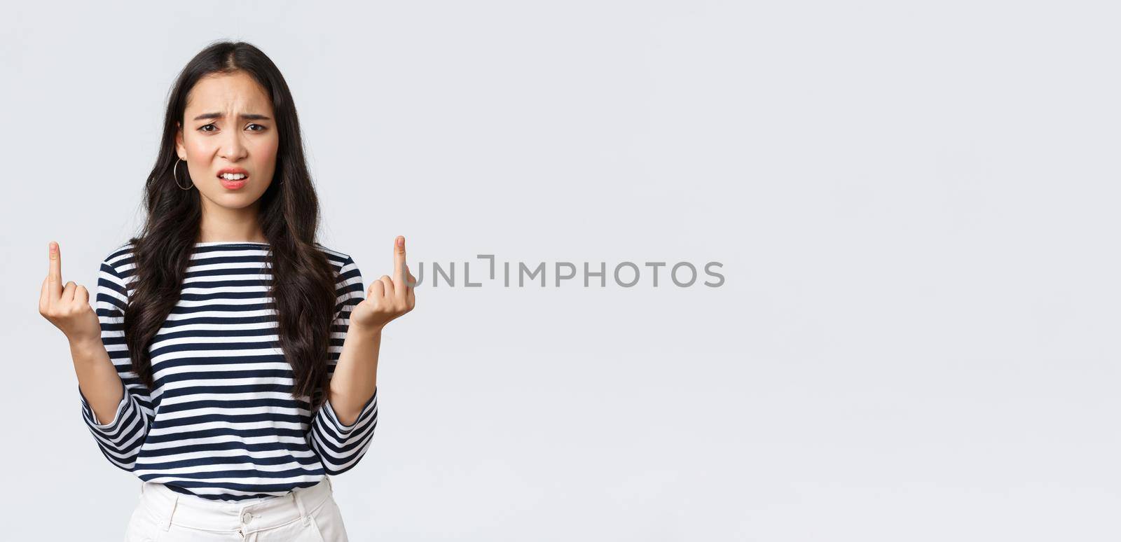 Lifestyle, beauty and fashion, people emotions concept. Annoyed pissed-off asian woman stare bothered and displeased, showing middle-fingers careless what people say, white background.