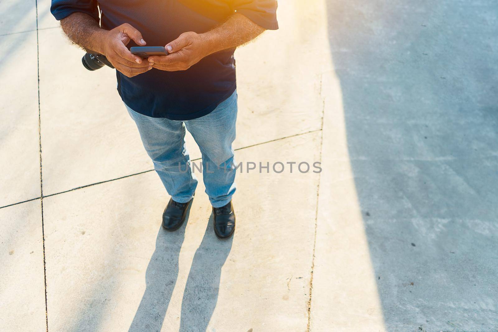 Top view of an unrecognizable latin man holding his cellphone in a park outdoors by cfalvarez