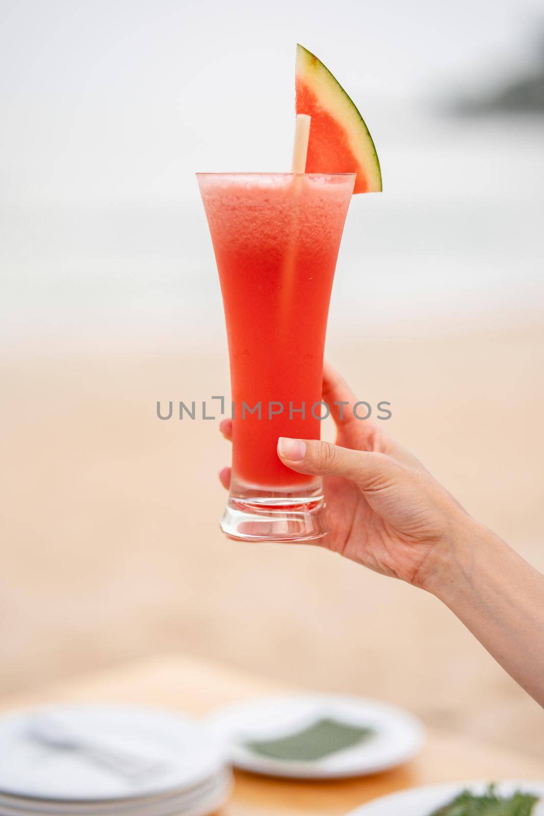 Glass of watermelon juice with blur ocean background.