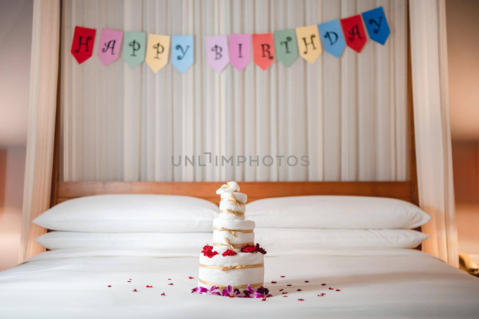 Celebrating Birthday, surprise in bed with Happy birthday banner and towel cake.