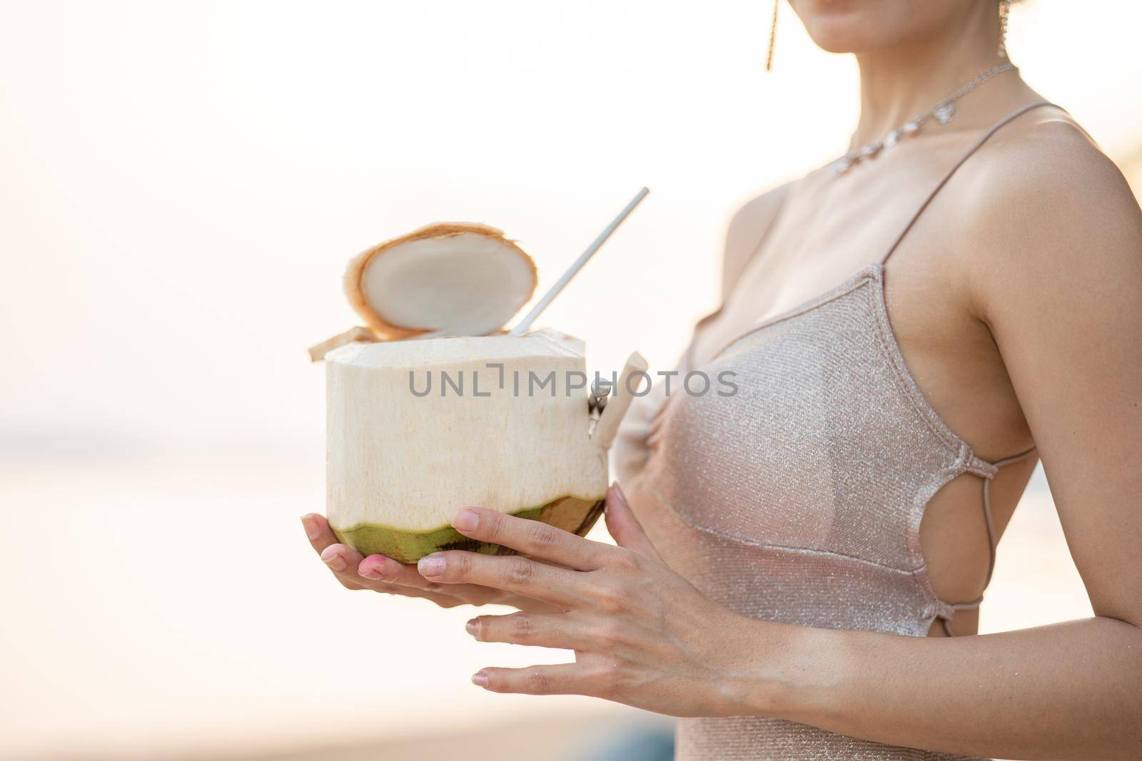 Woman drinking fresh coconut on the beach, romantic sunset moment. summer vacation.