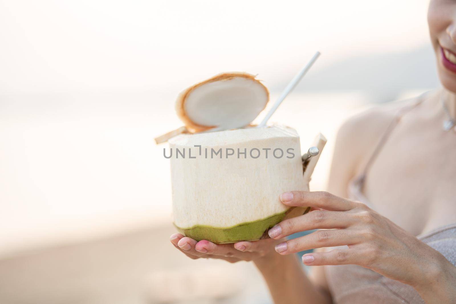 Woman drinking fresh coconut on the beach, romantic sunset moment. summer vacation.