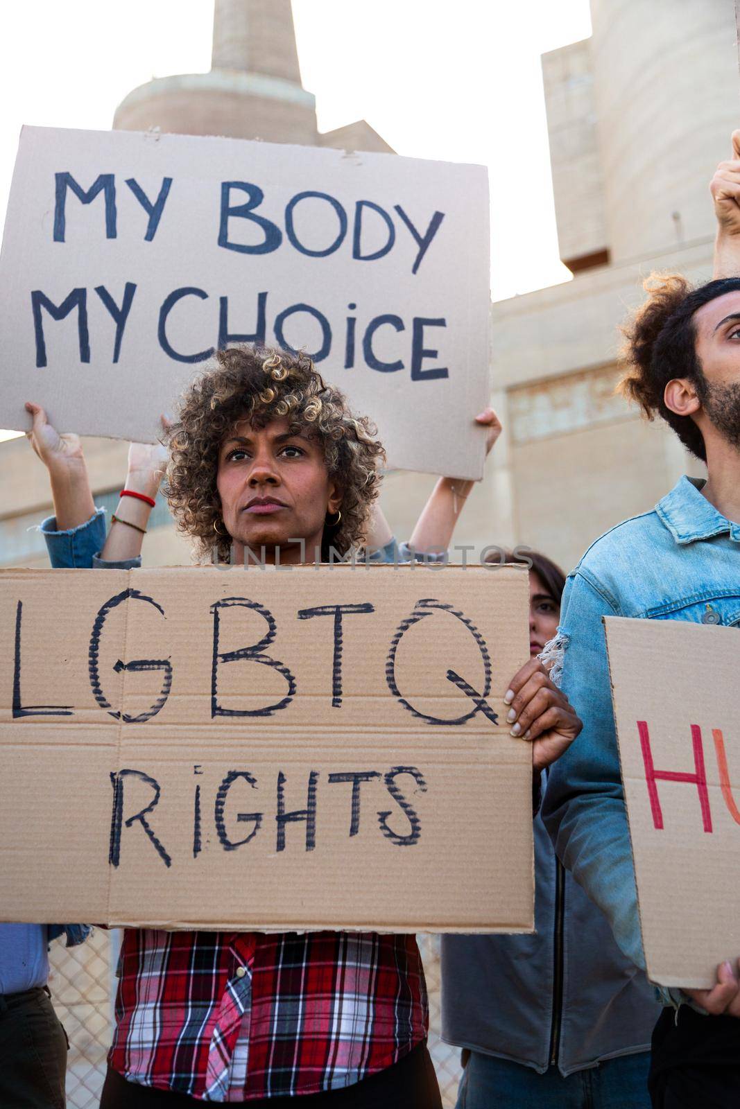 African American woman holding LGBTQ rights cardboard signboard in demonstration protesting. Vertical image. by Hoverstock