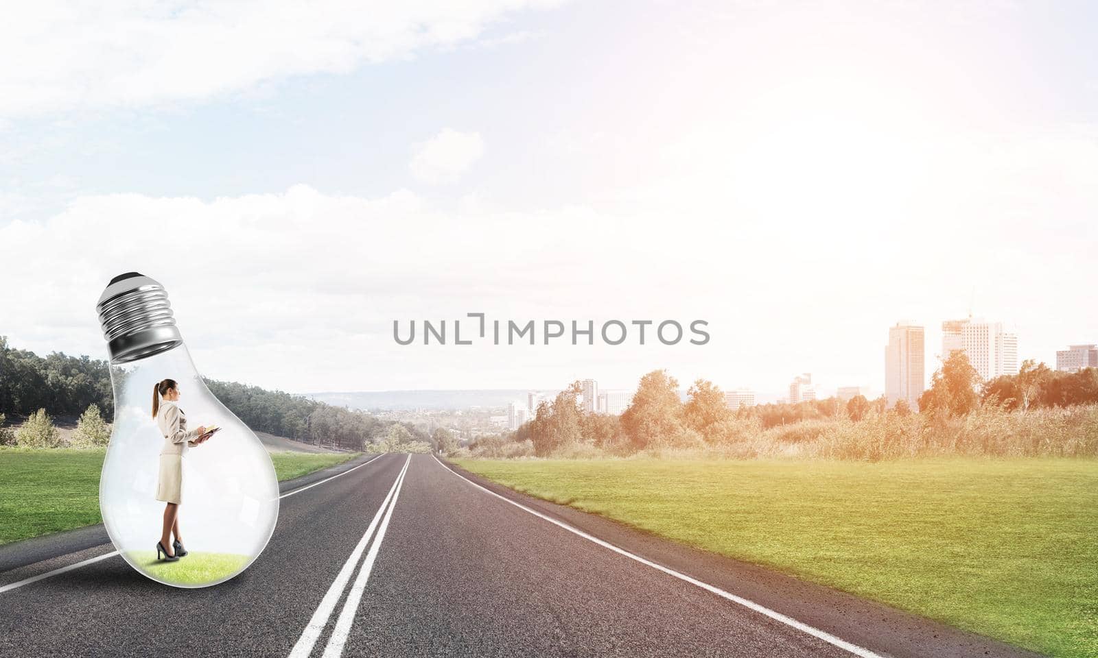 Young businesswoman trapped inside of light bulb on asphalt road