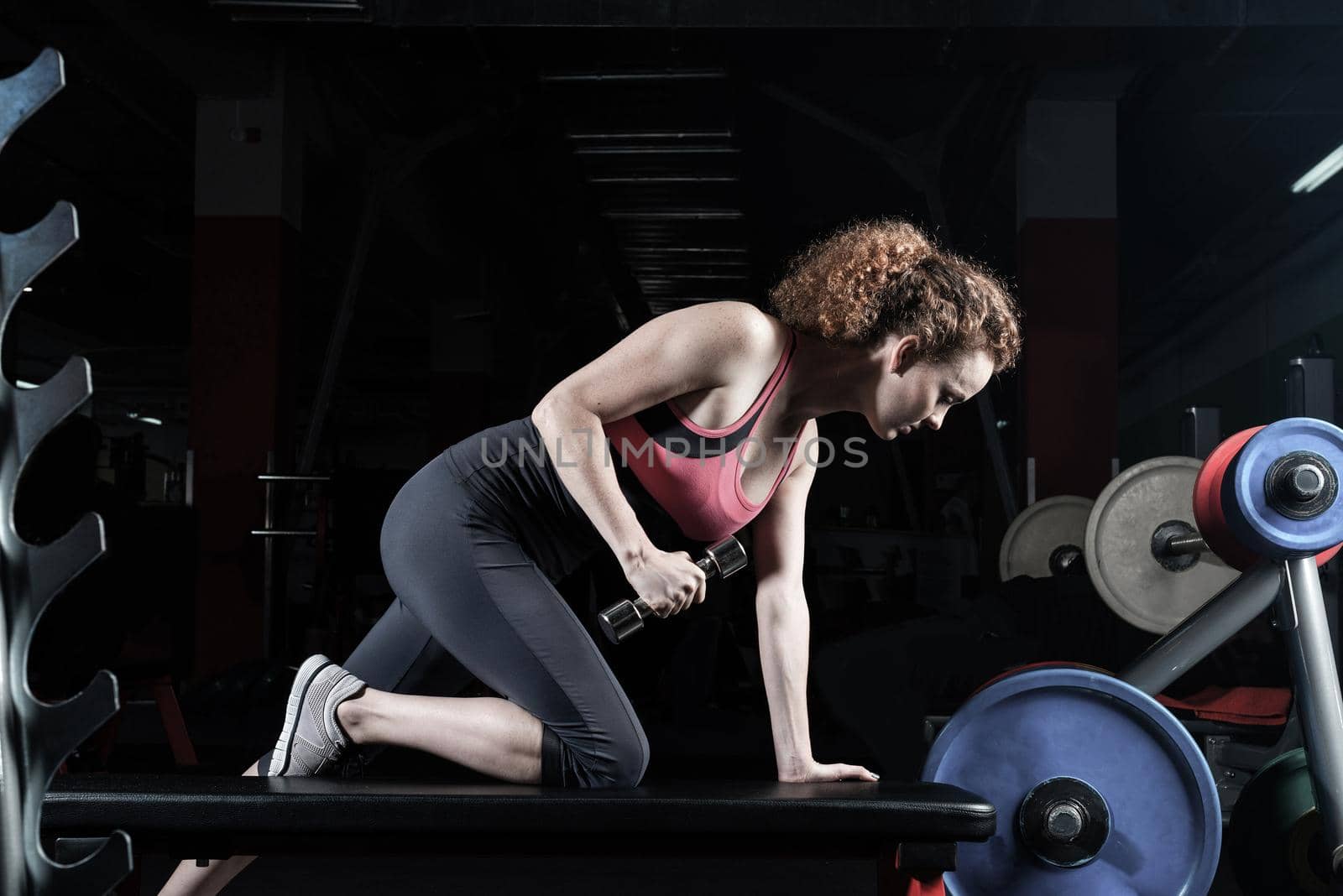 Woman bodybuilder engaged with dumbbells in the gym.