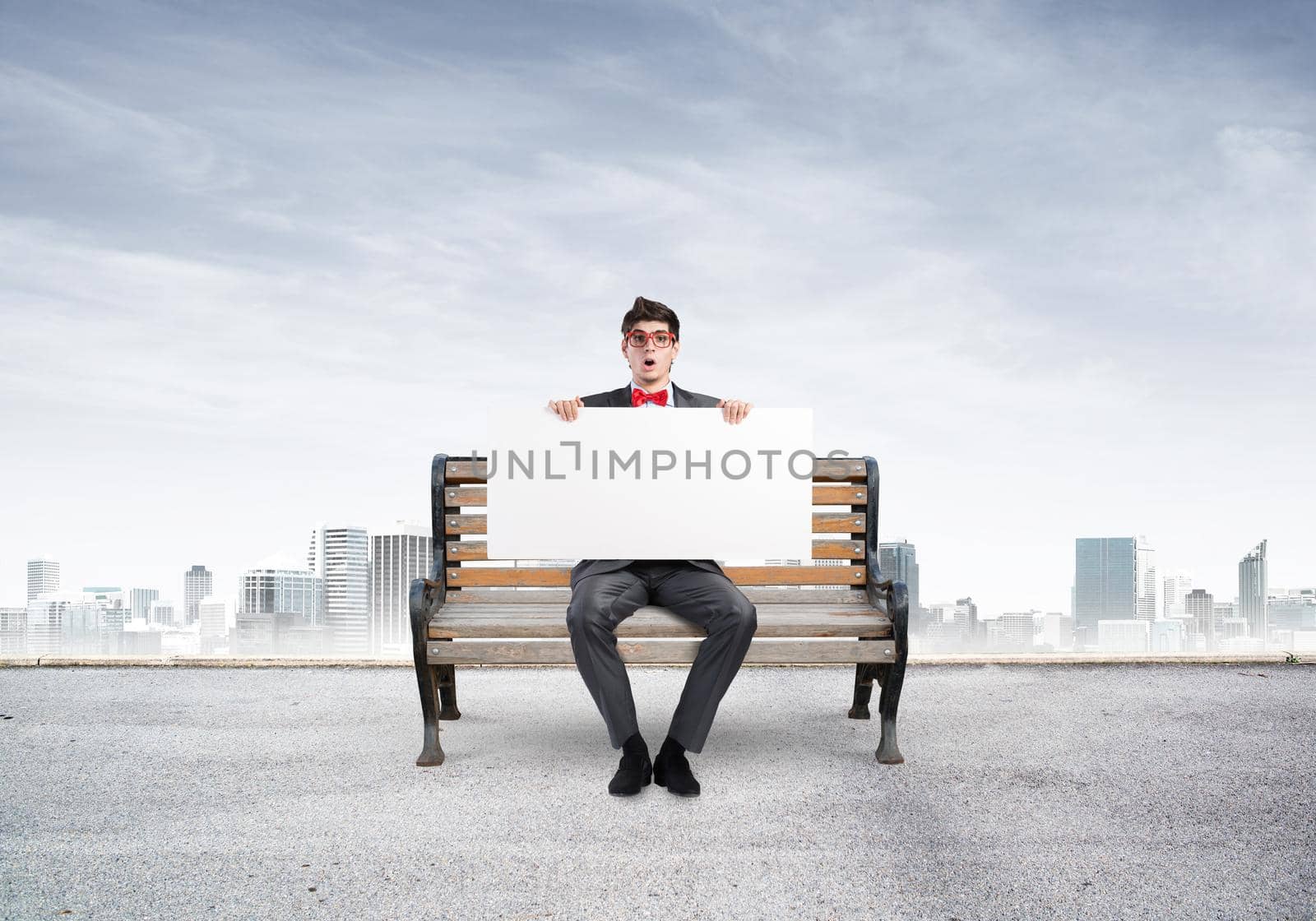 Young businessman holds a large white banner. sits on the bench