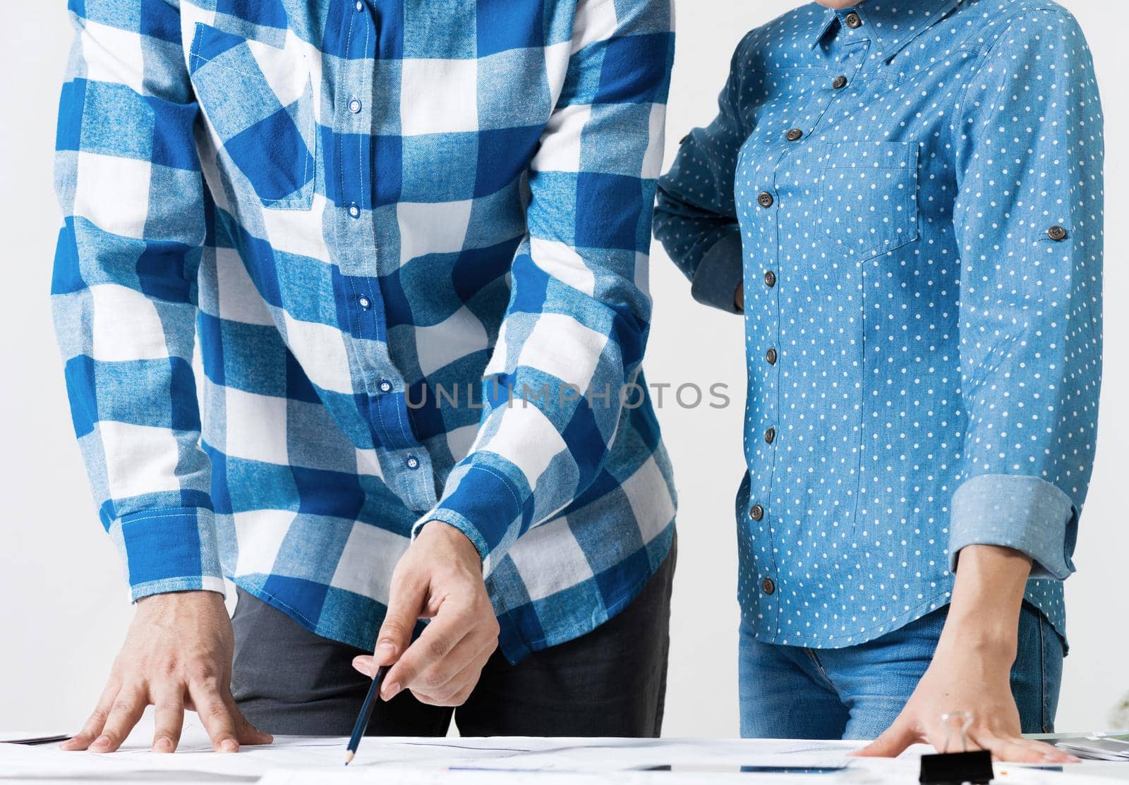 Design project discussing in architecture studio. Architect analyzing paper blueprint. Close up man hand pointing with pencil on construction drawing. Professional building, engineering and renovation