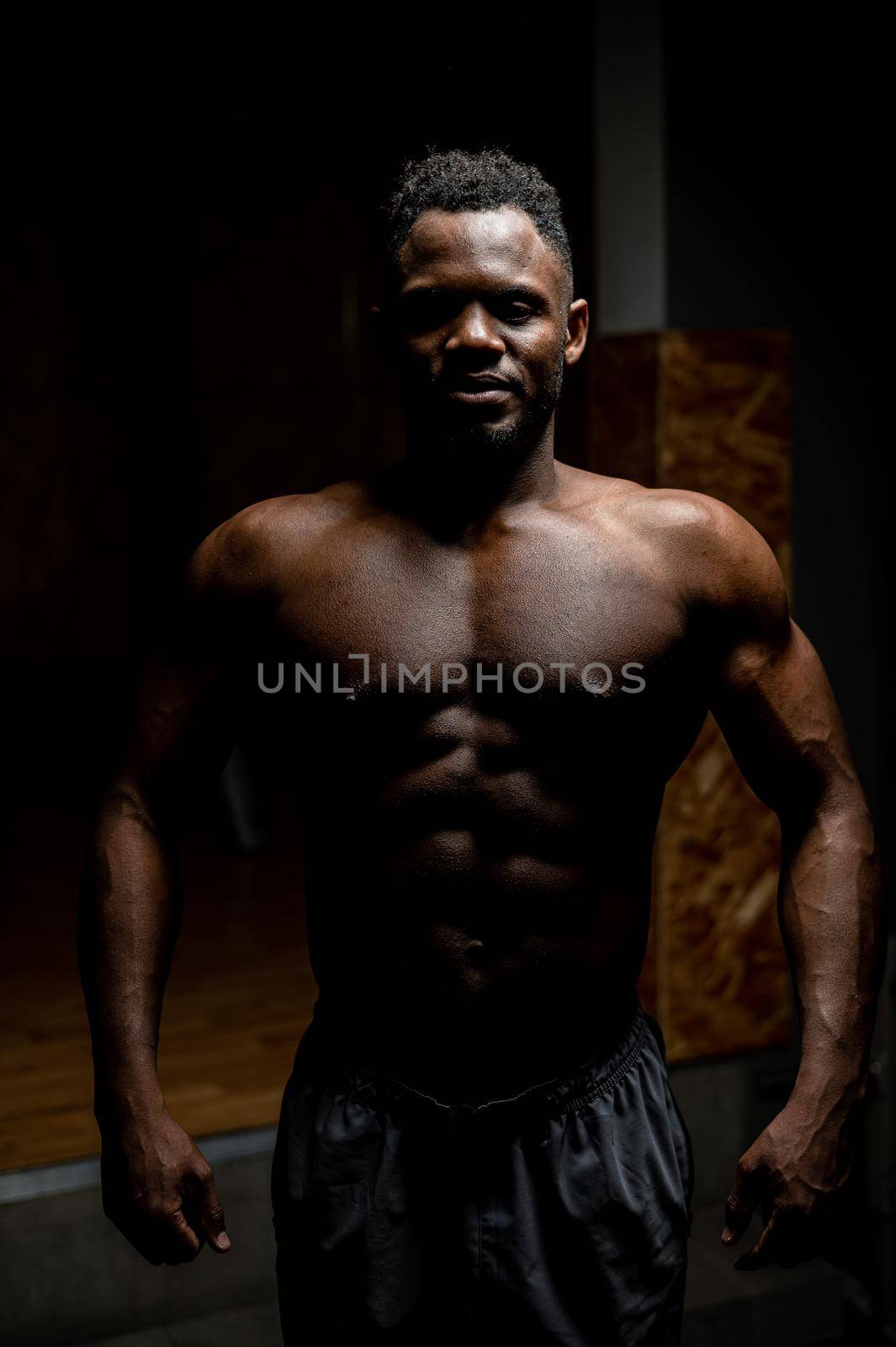 Portrait of an African American man with a naked torso in a dark studio. Muscular guy. by mrwed54
